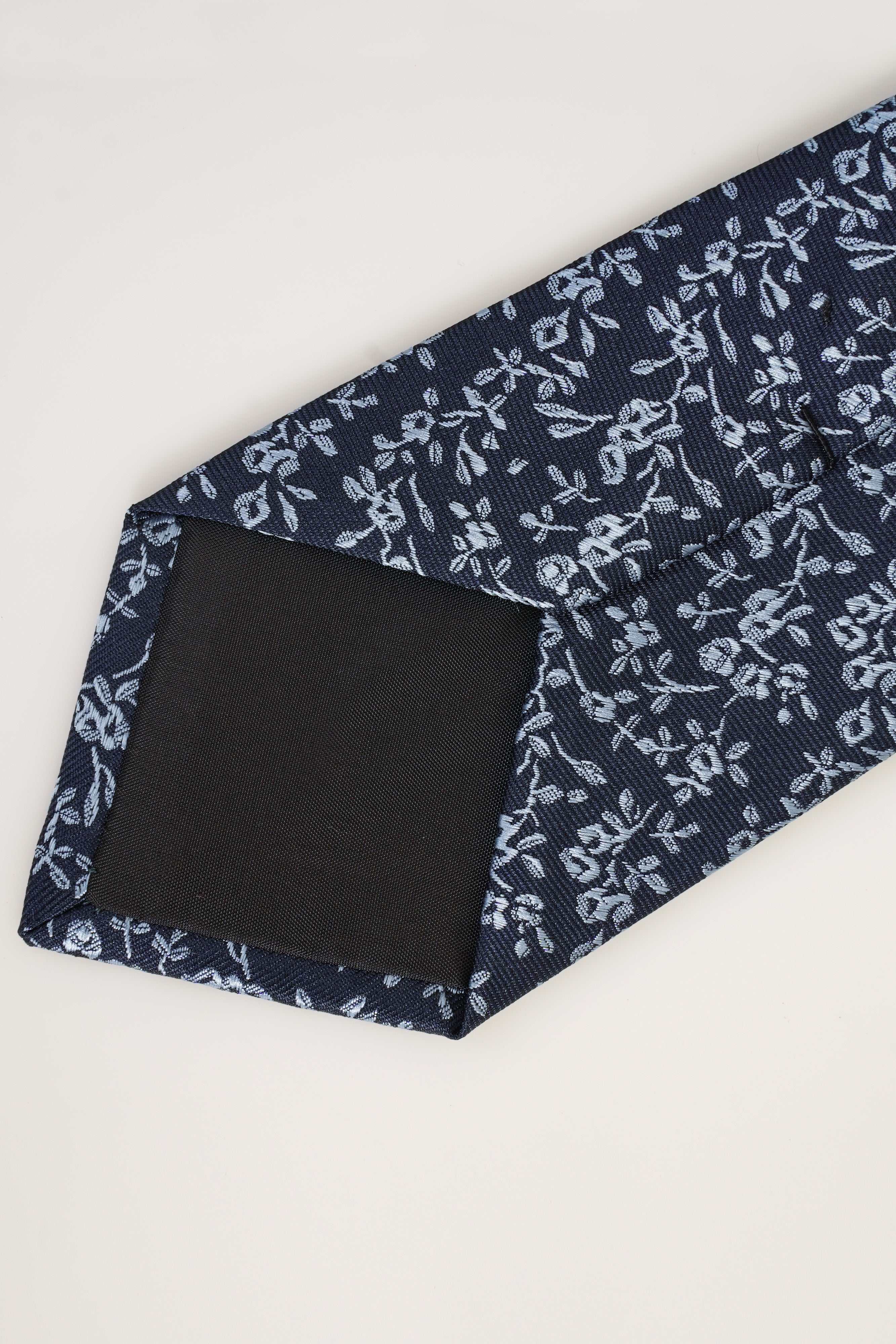 Poly silk tie with woven texture and label at tip, dark navy with white motifs