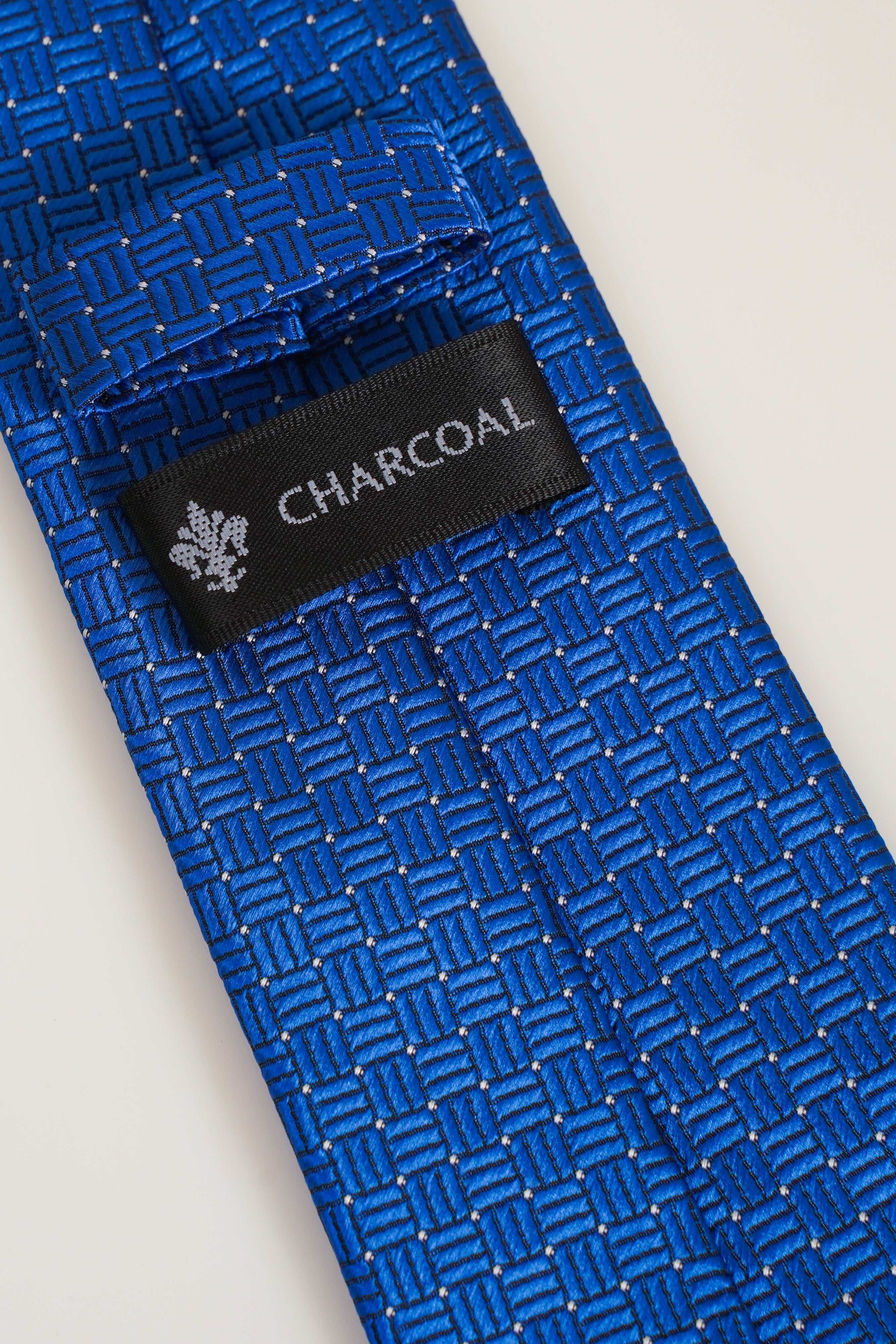 Blue patterned tie label reading CHARCOAL on woven background