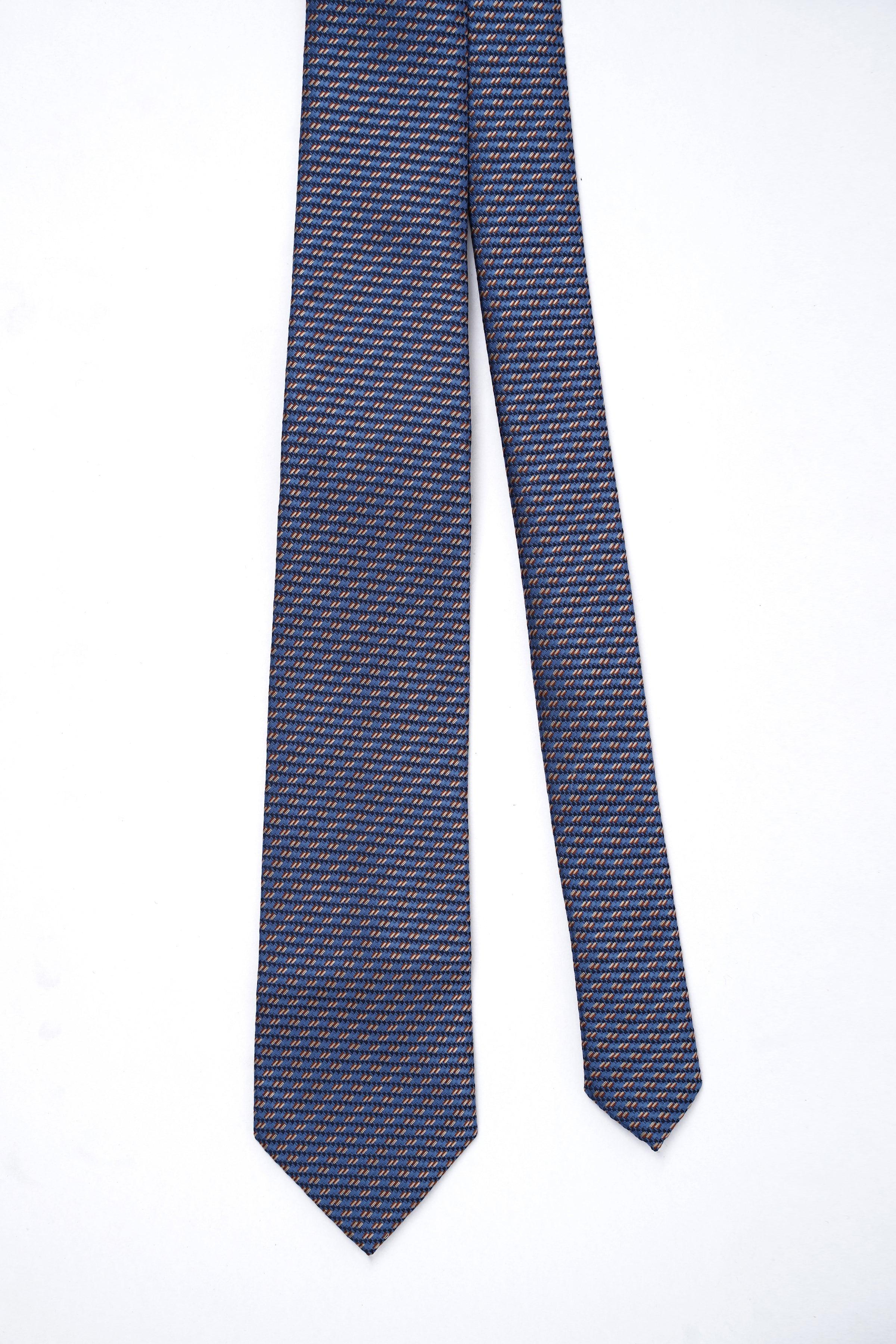 Poly silk tie laid flat, navy with orange micro-pattern, pointed end