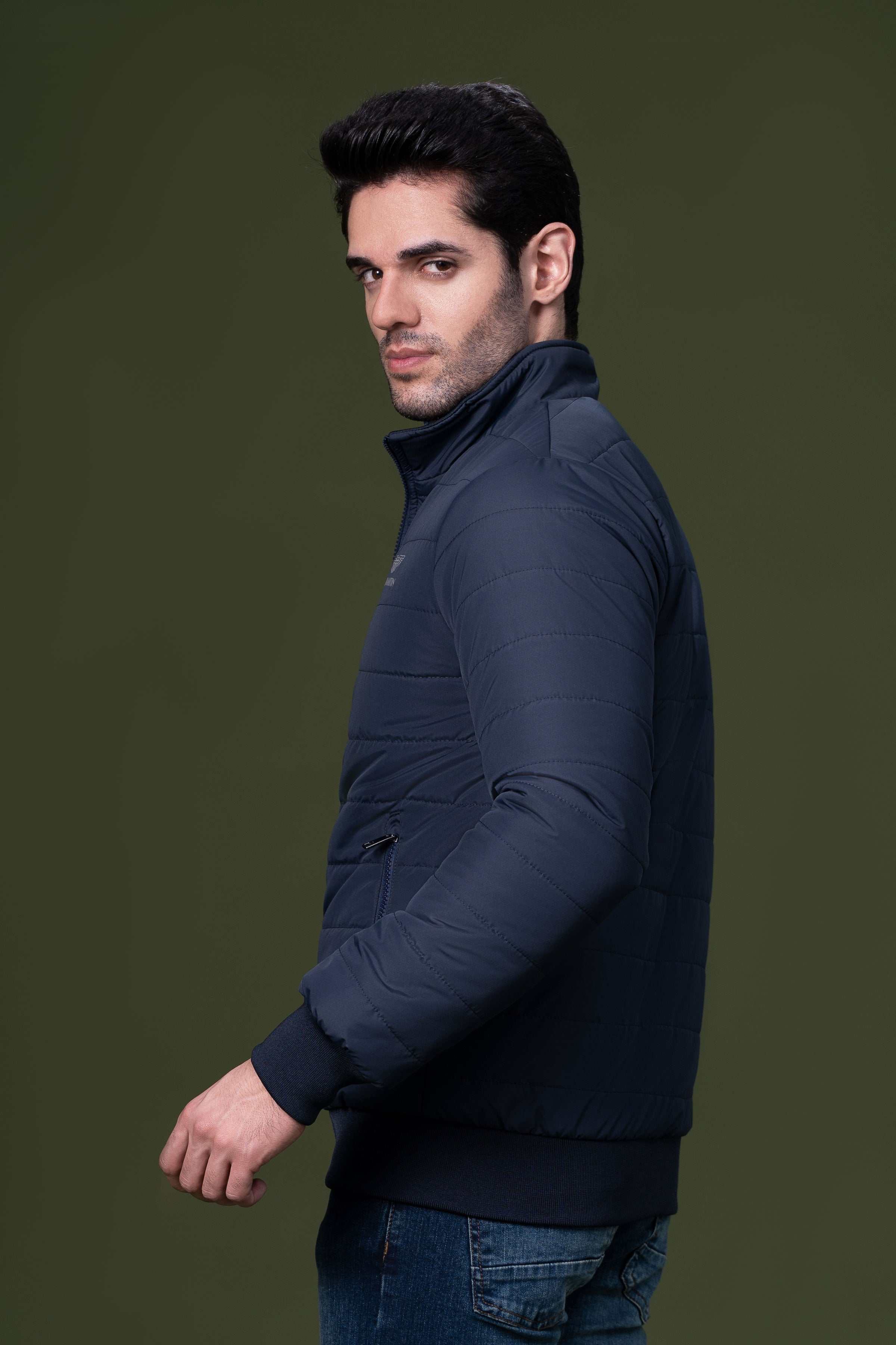 Navy puffer jacket side profile with sleeve quilting and ribbed hem