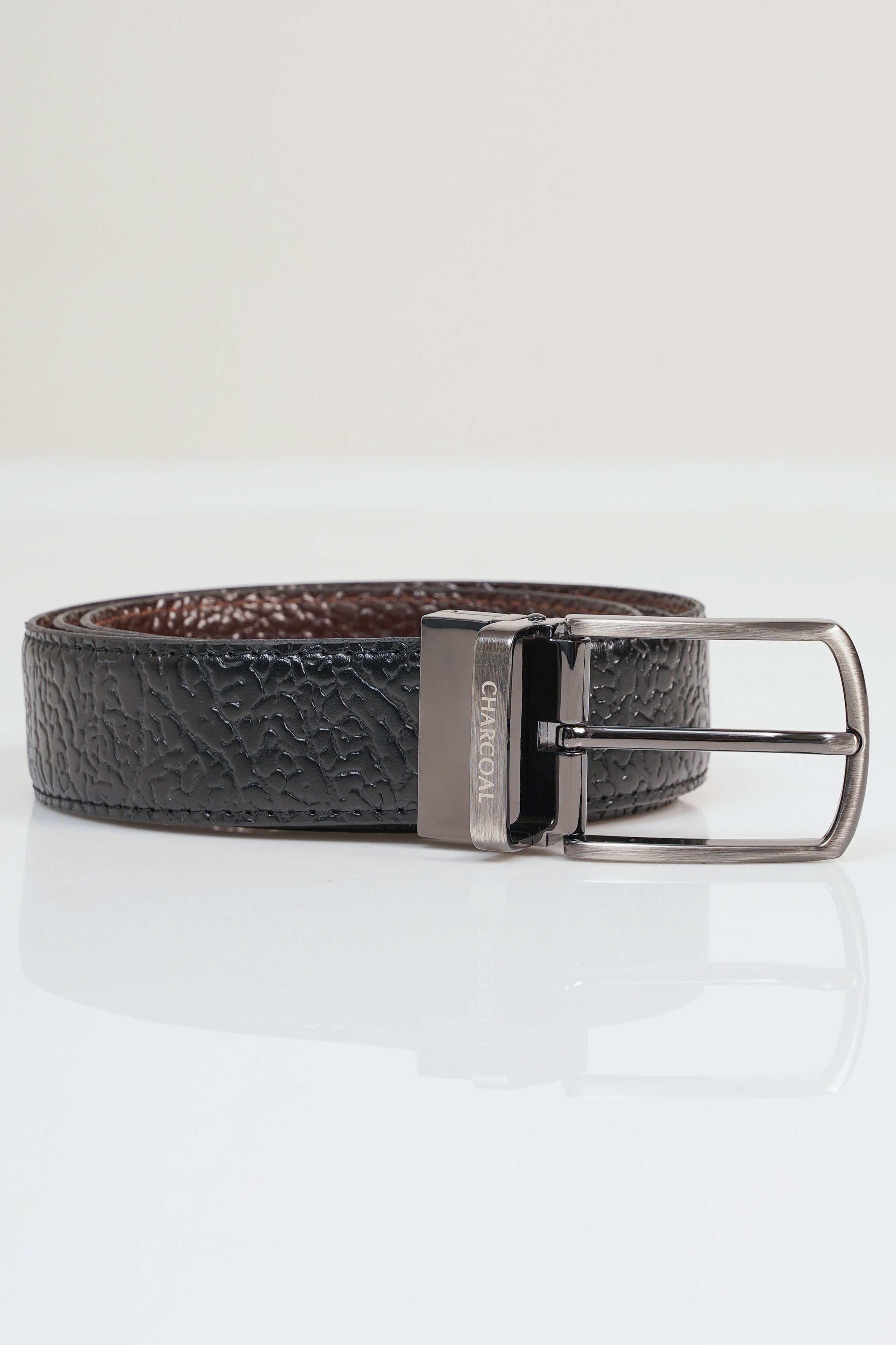 Reversible leather belt with textured dark strap and silver-tone buckle.