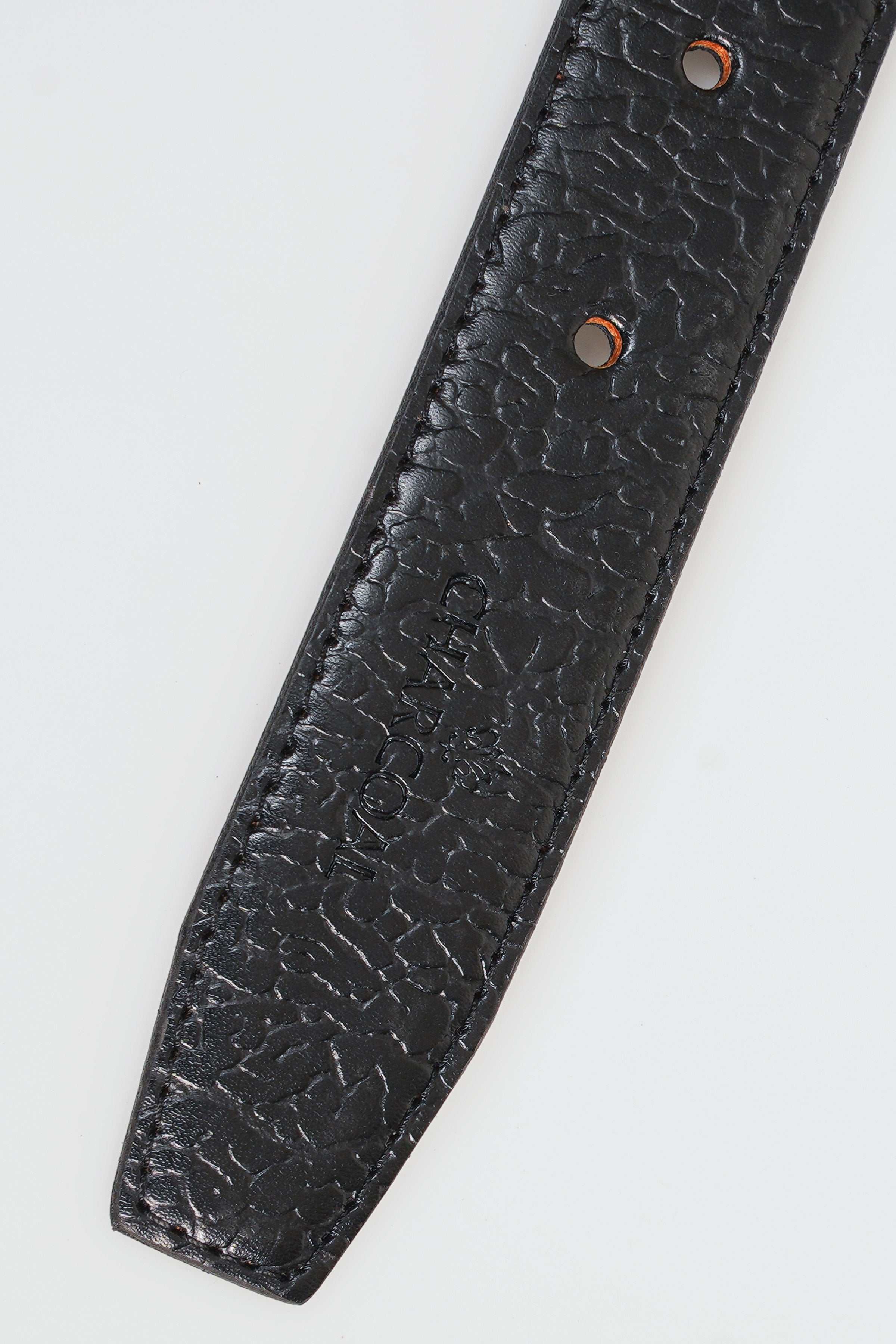 Dark textured leather belt strap end with two metal eyelets.