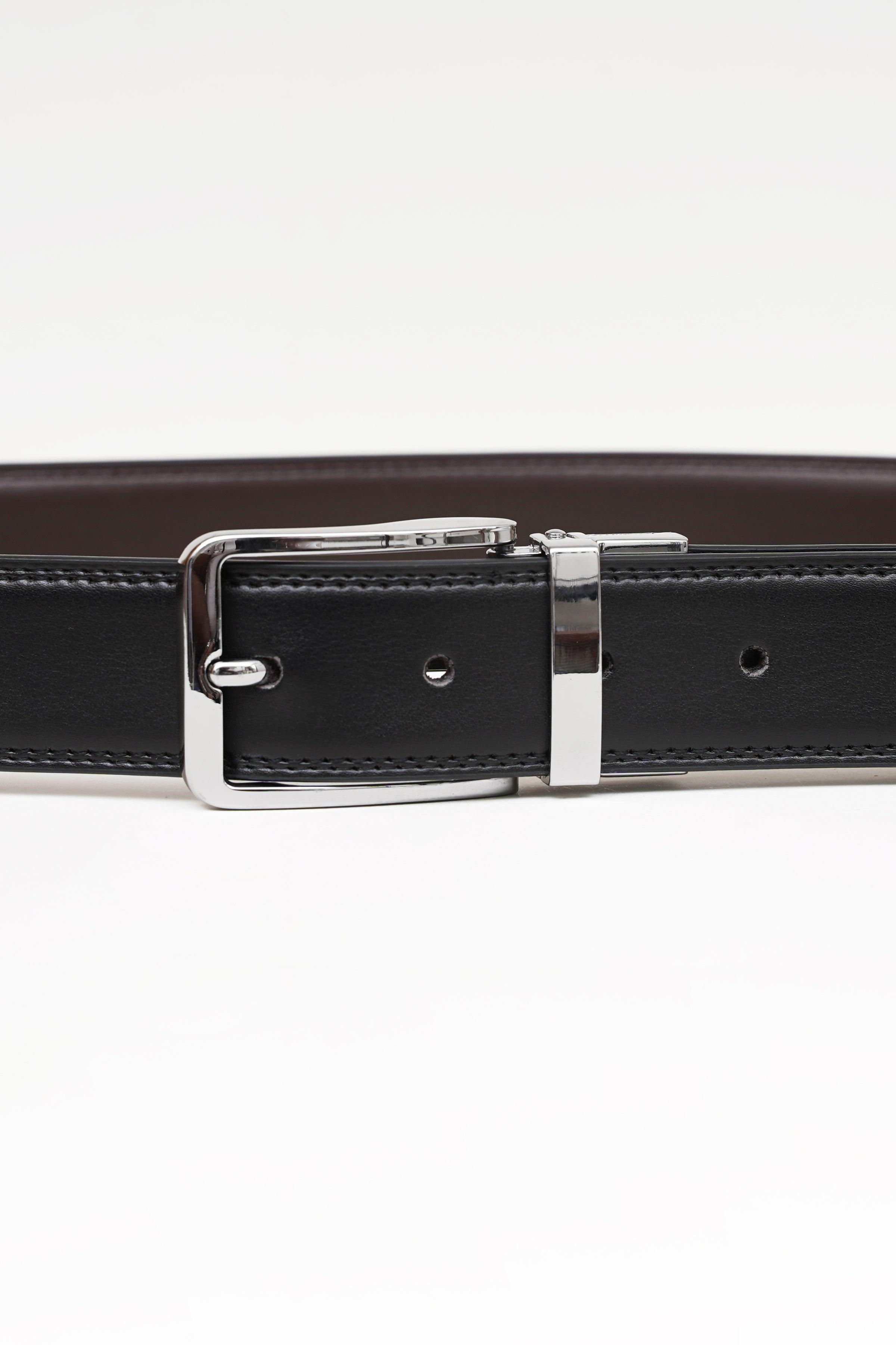 Reversible belt buckle close-up on dark strap with stitched edge and holes