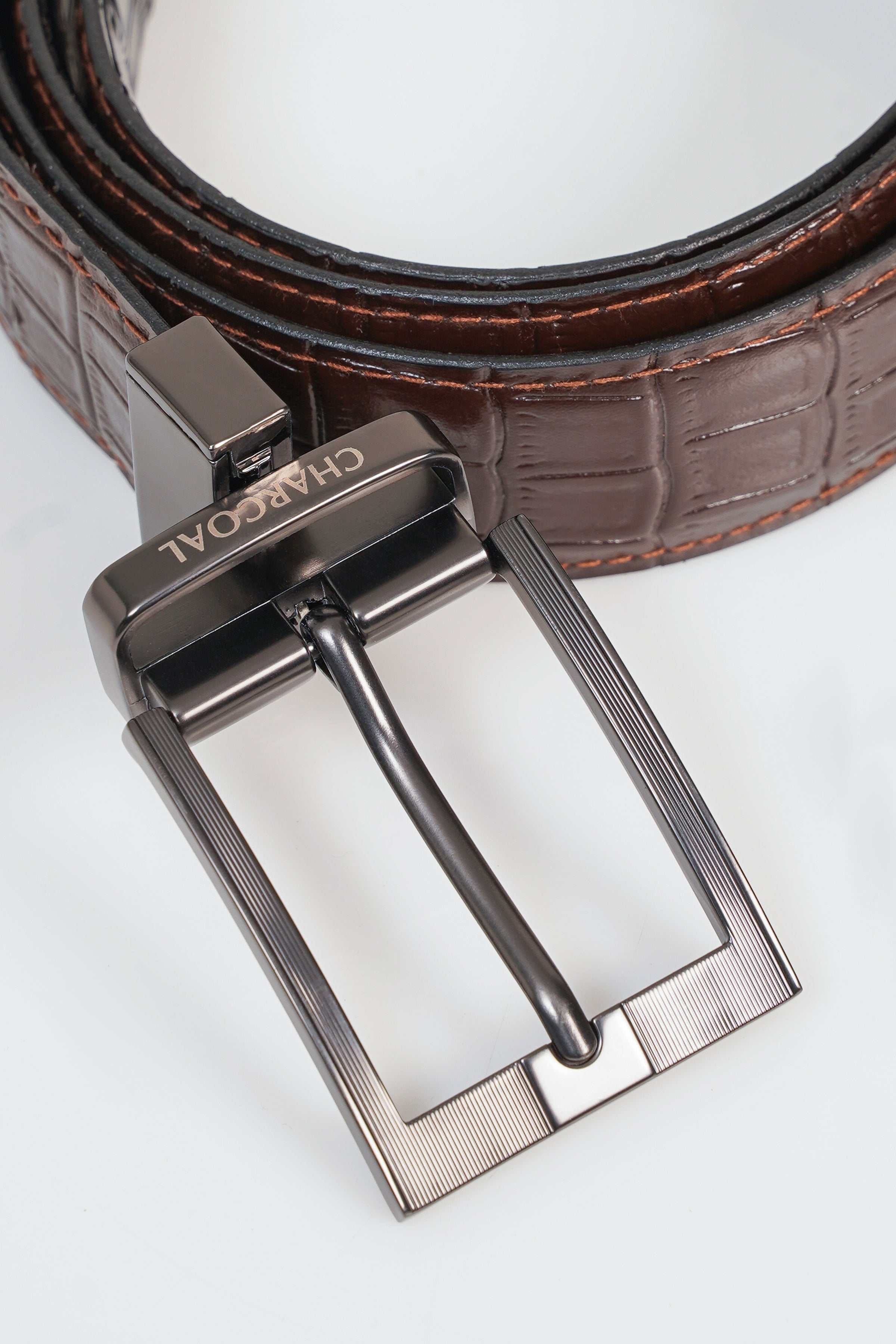 Reversible belt close-up: silver buckle with embossed brown strap and stitched edges
