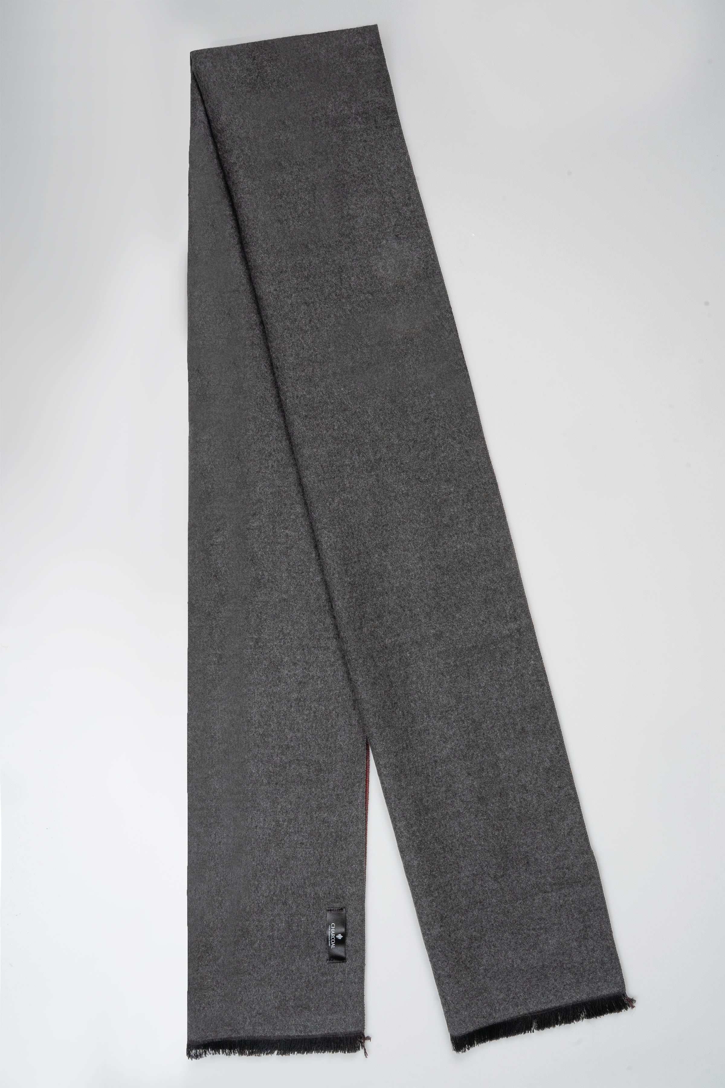 Charcoal gray scarf laid flat with frayed ends and small end label