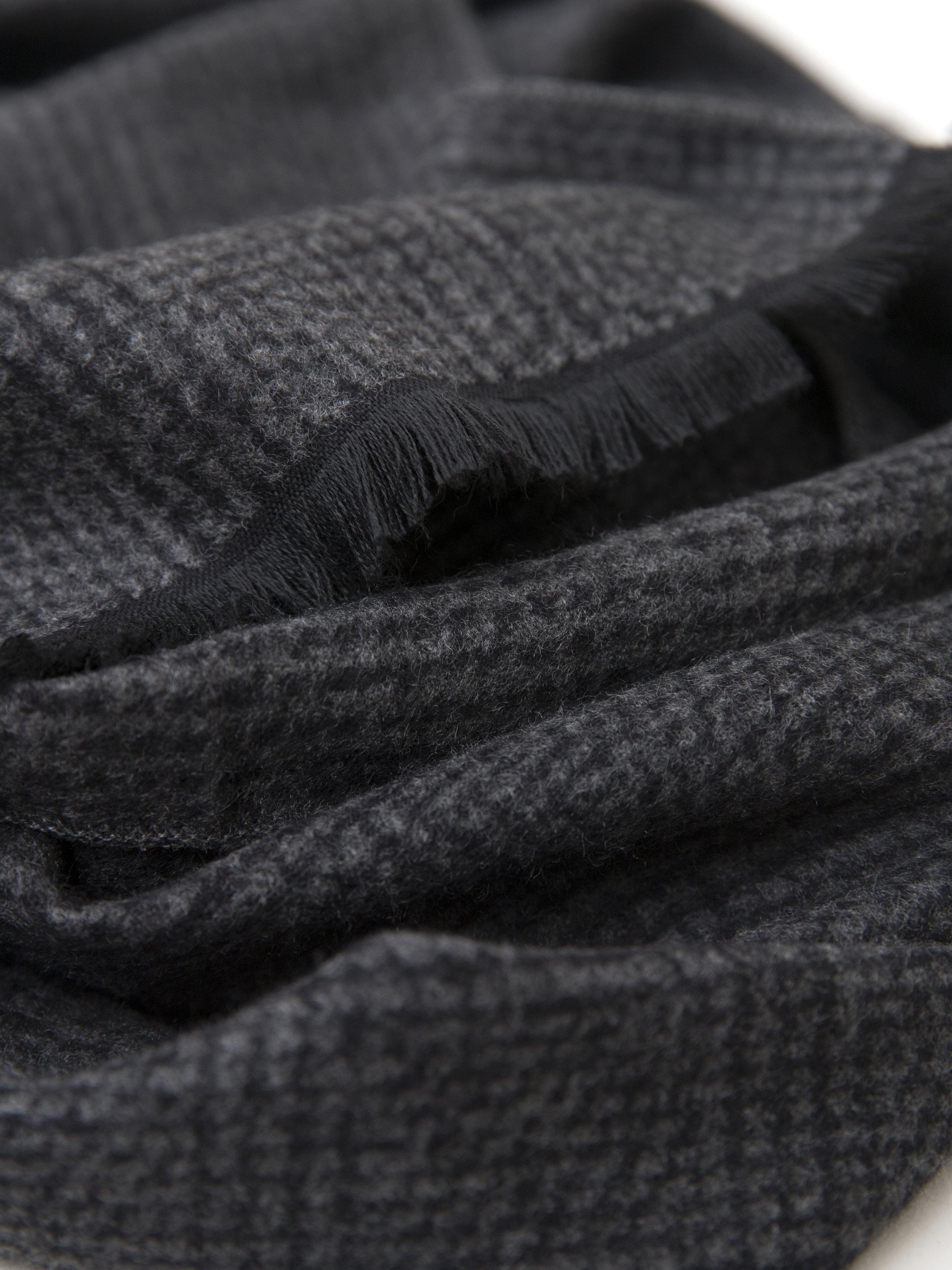 Dark gray scarf detail with woven texture and short fringe edge