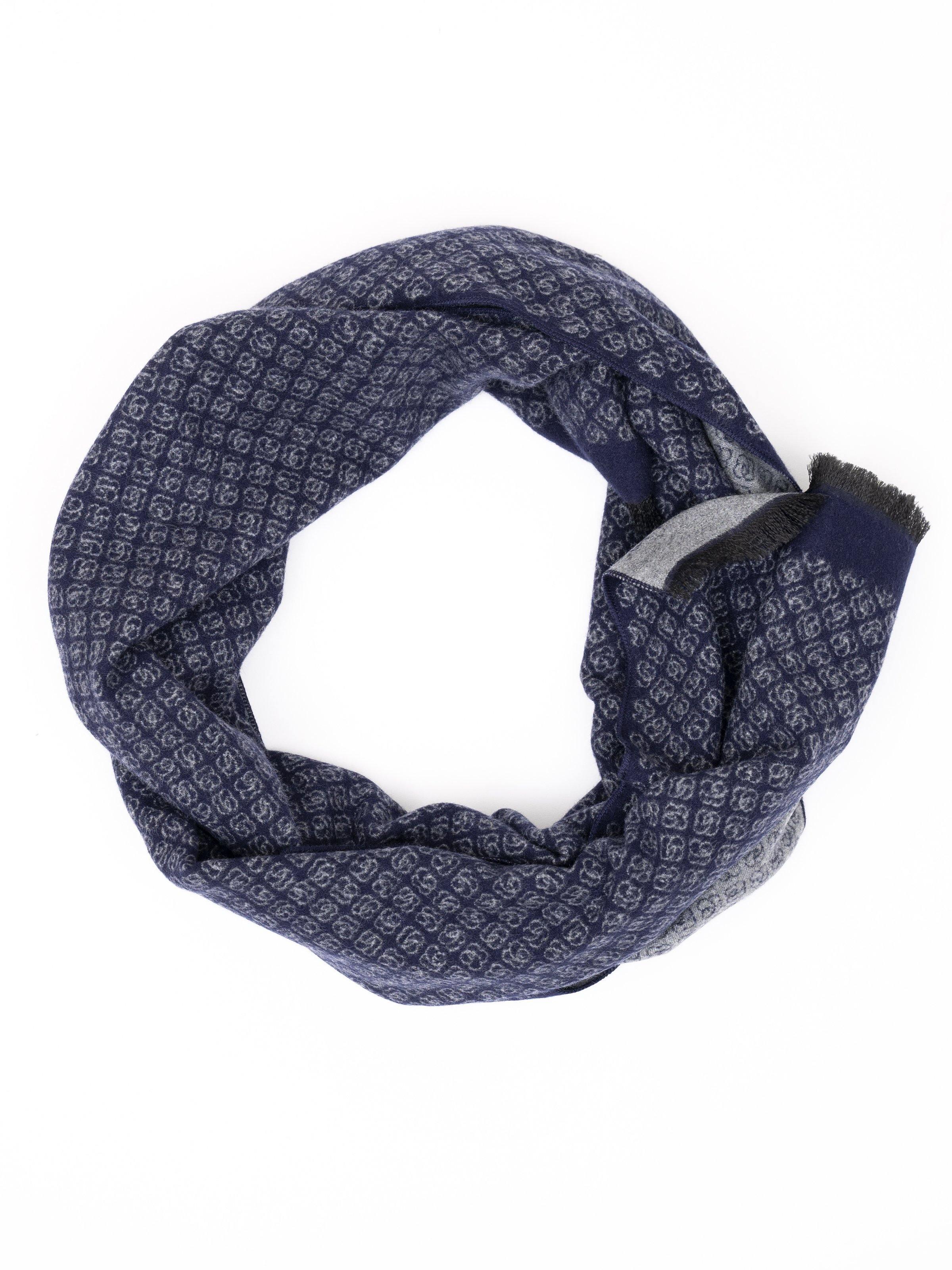 Navy patterned scarf with repeating motif, looped with soft fringe edges.