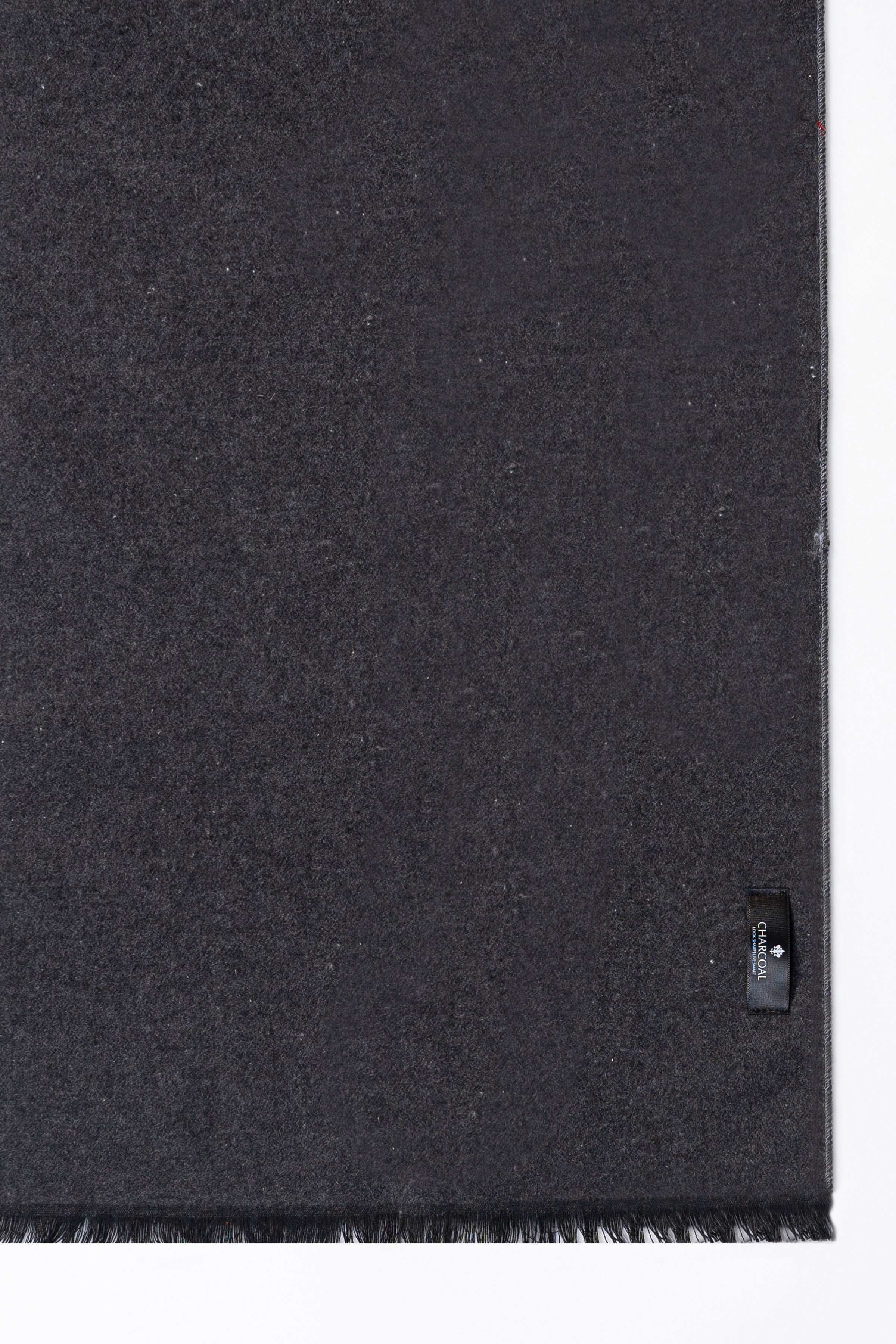 Scarf fabric close-up in dark gray with woven label and frayed edge