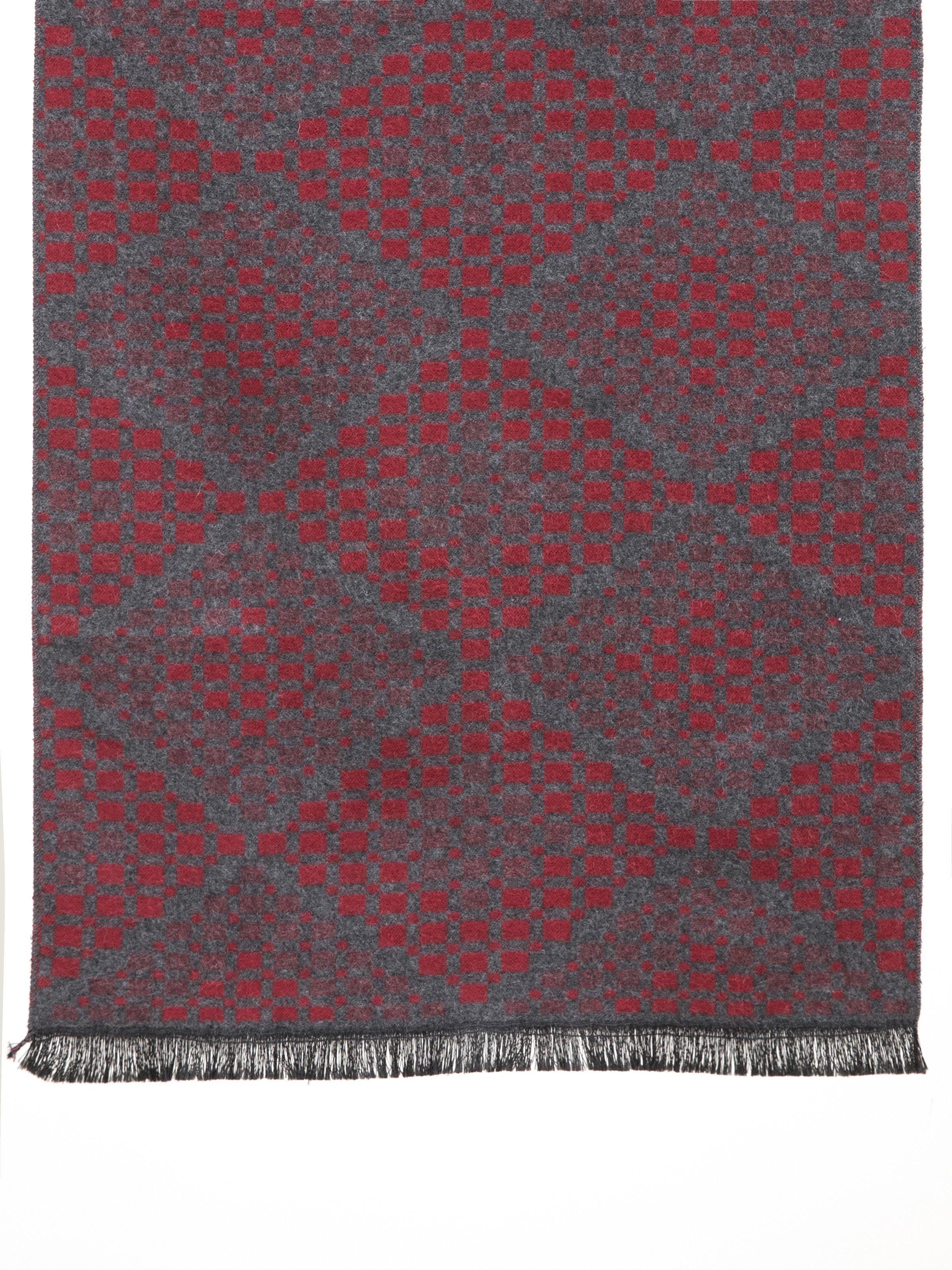 Scarf fabric close-up with geometric pattern in deep red on dark gray, fringed hem