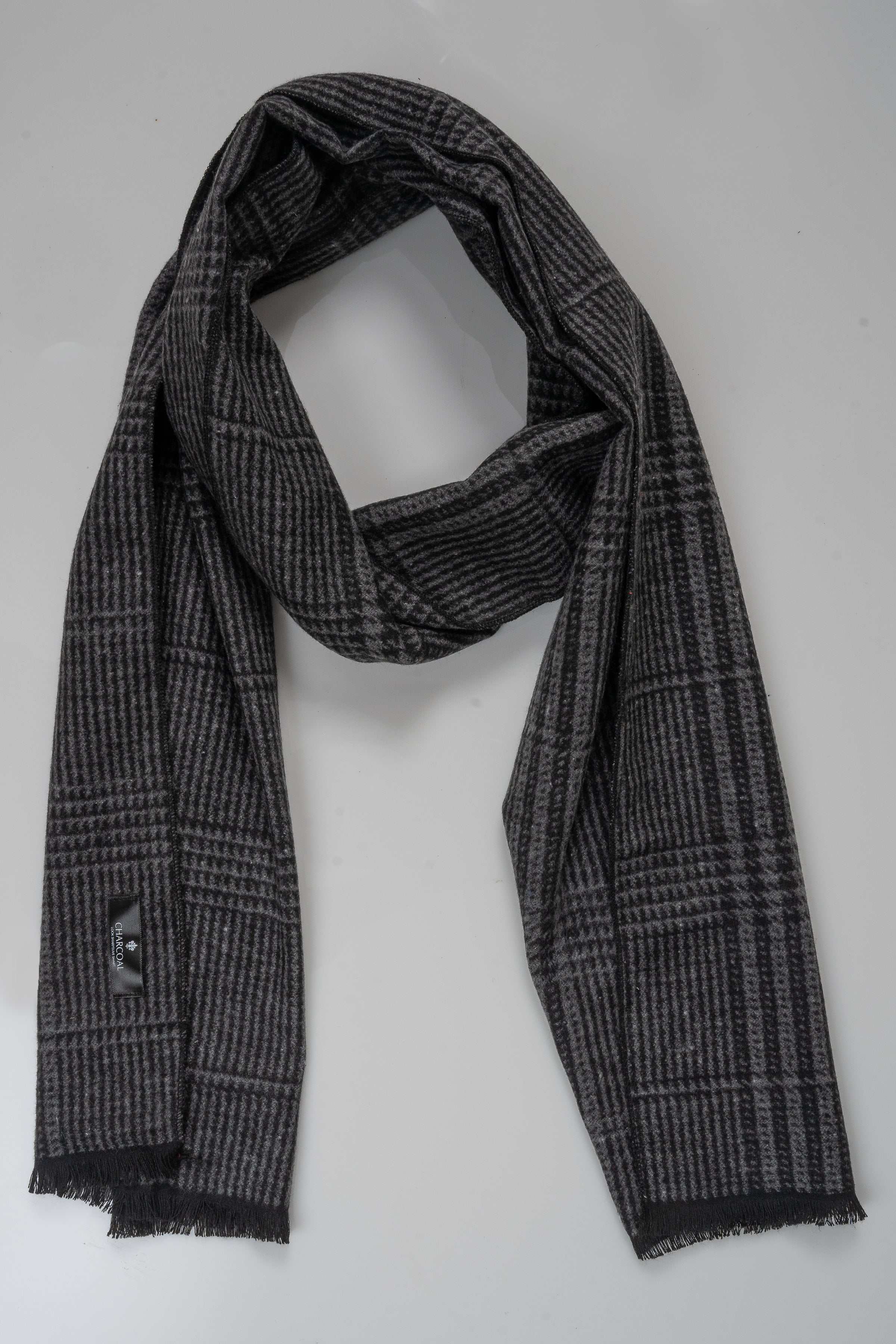 Charcoal plaid scarf draped on mannequin with fringed ends and logo tag