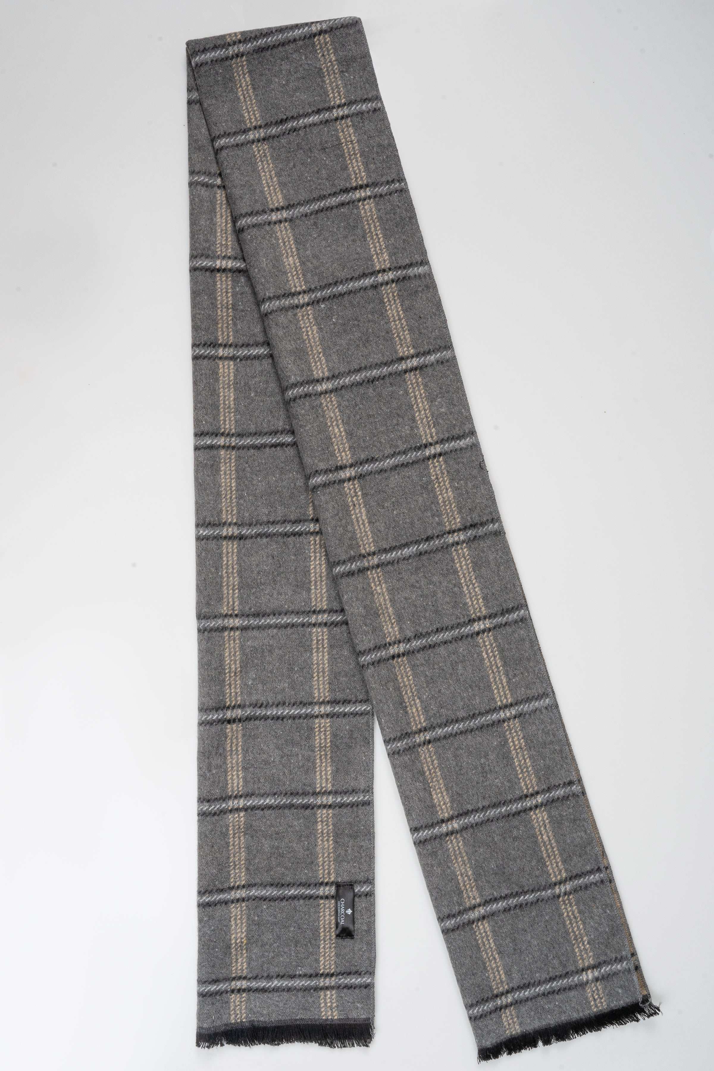 Grey plaid scarf with thin tan stripes and fringed ends, small stitched tag at corner.