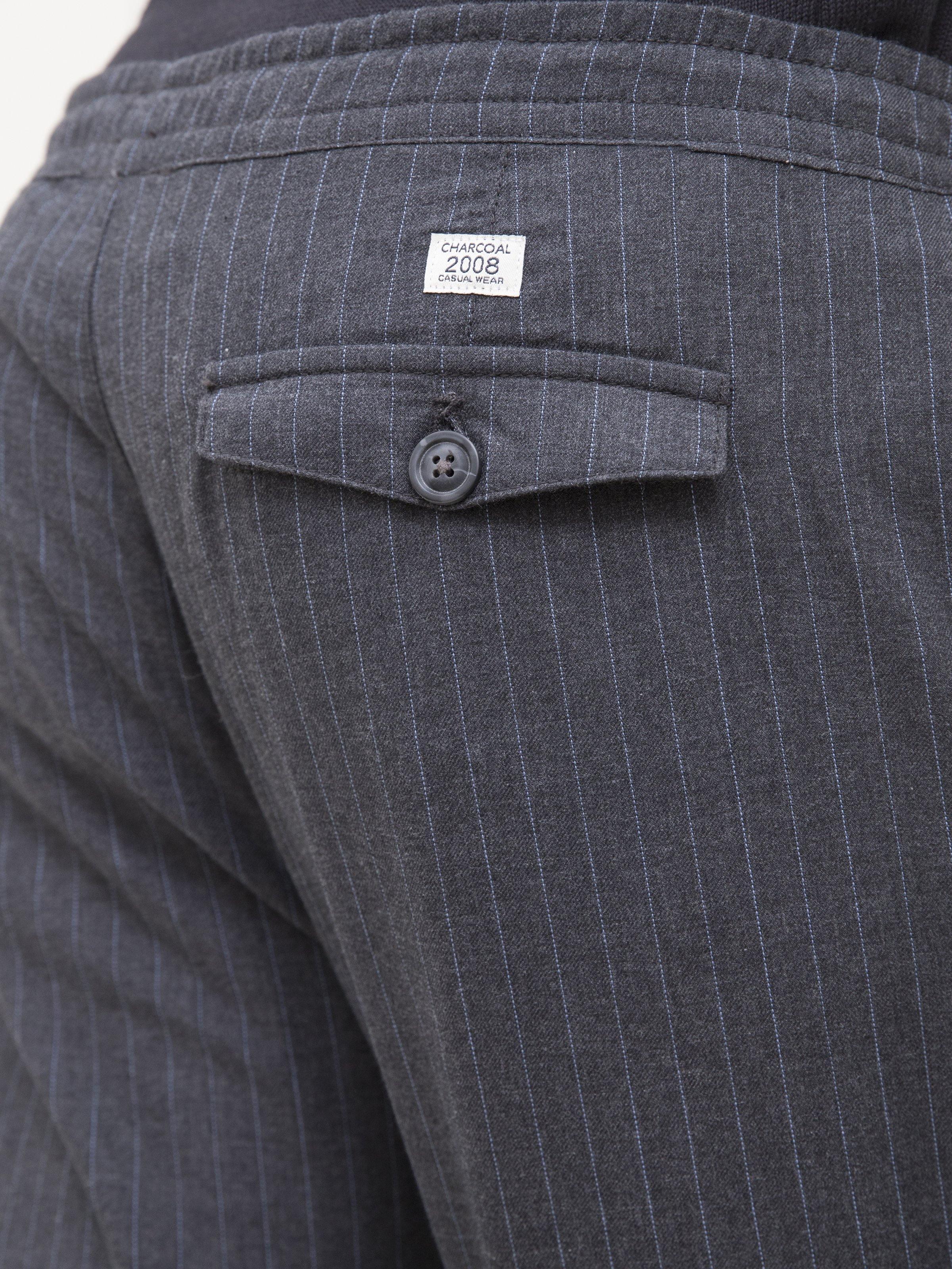 Charcoal black trousers close-up: buttoned side pocket and fabric label near waistband