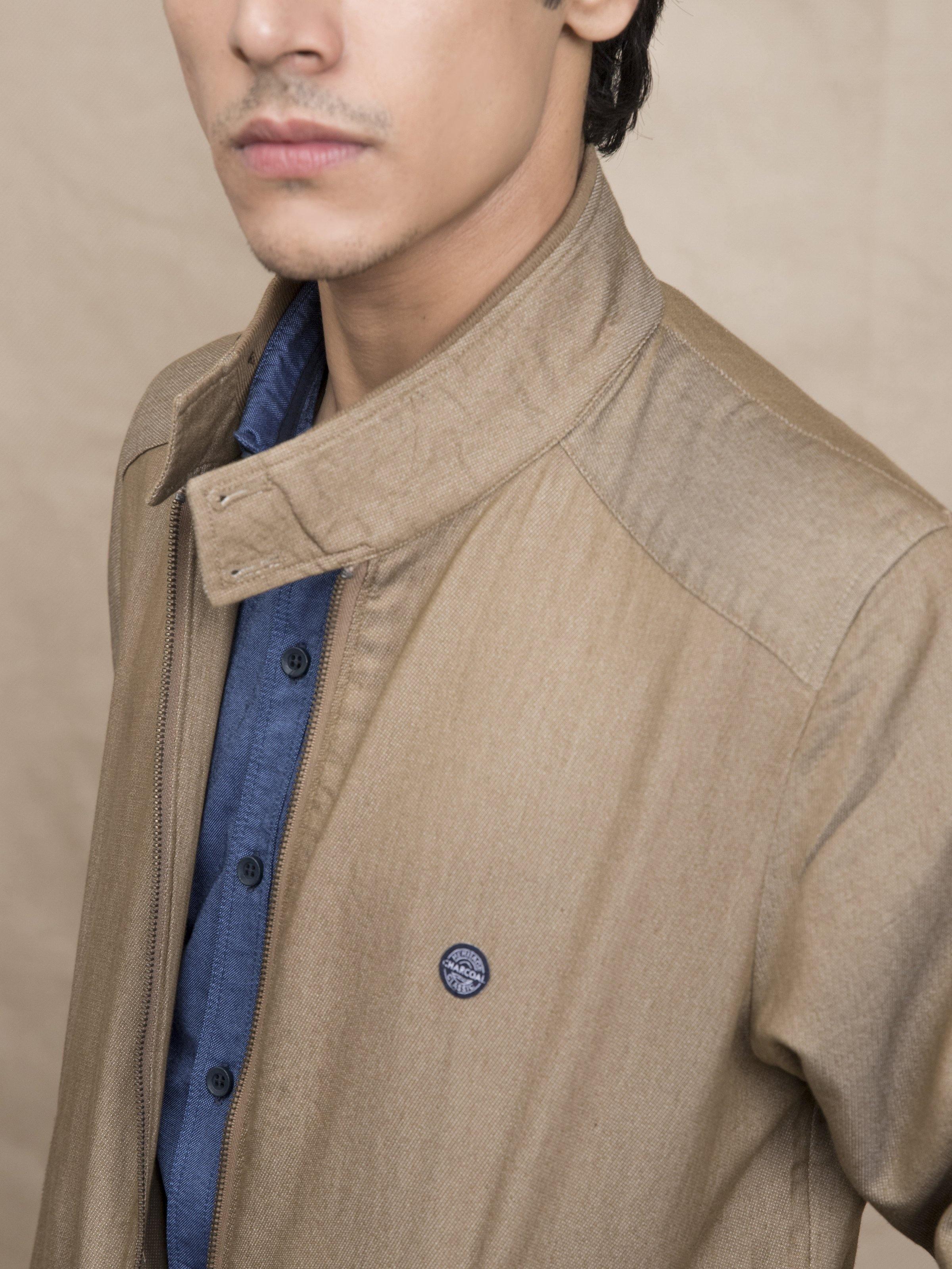 Light brown textured jacket with ban collar and round logo button on chest
