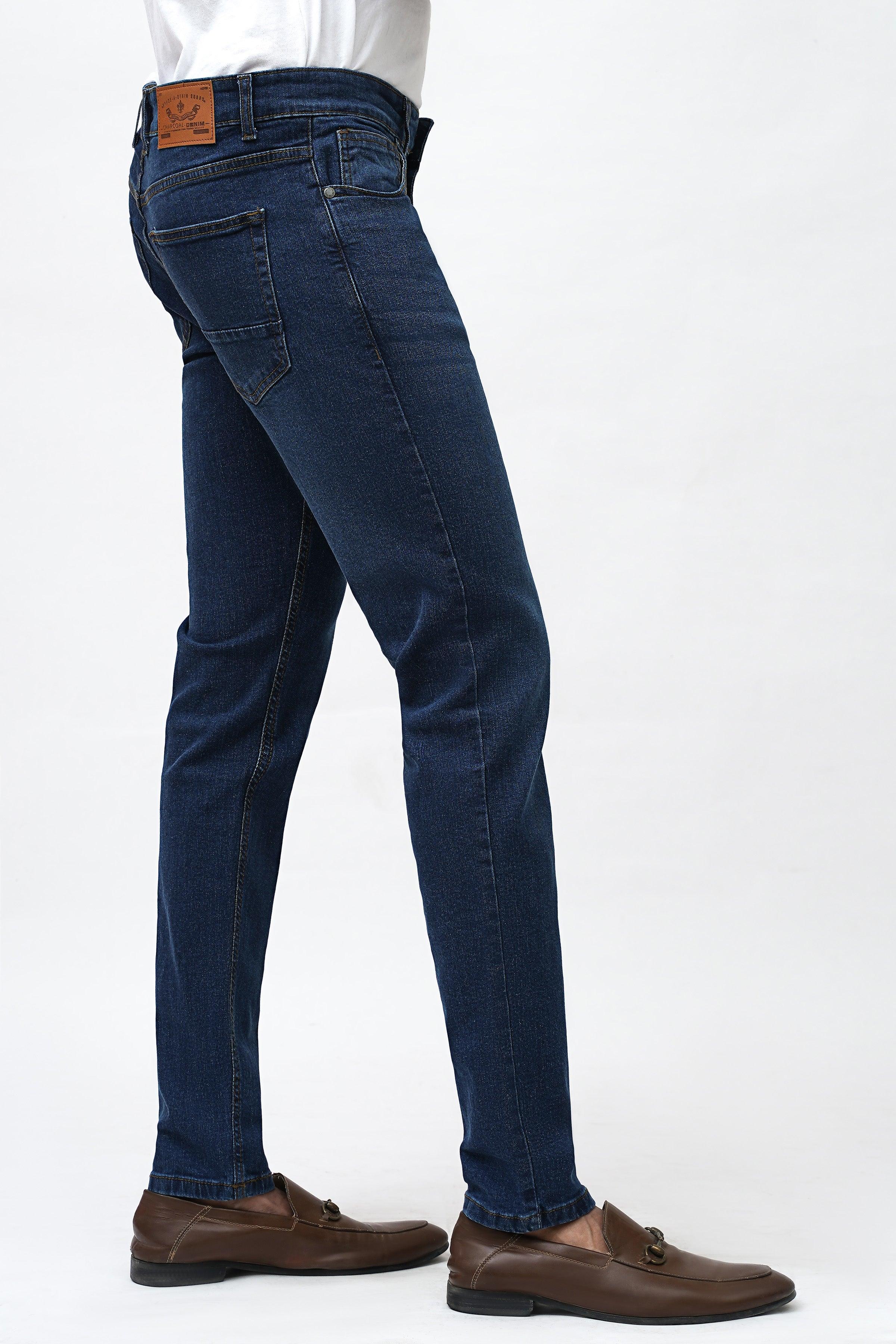Dark blue skinny jeans side view with five-pocket styling and tan label tag