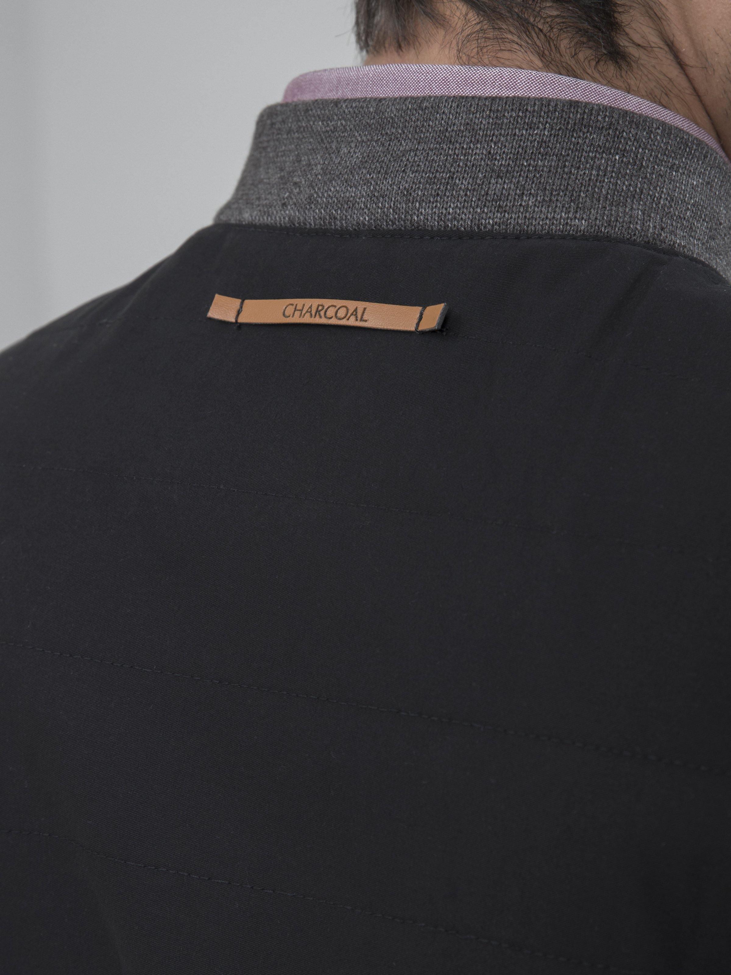 Sleeveless quilted jacket neckline close-up with brand label on dark vest