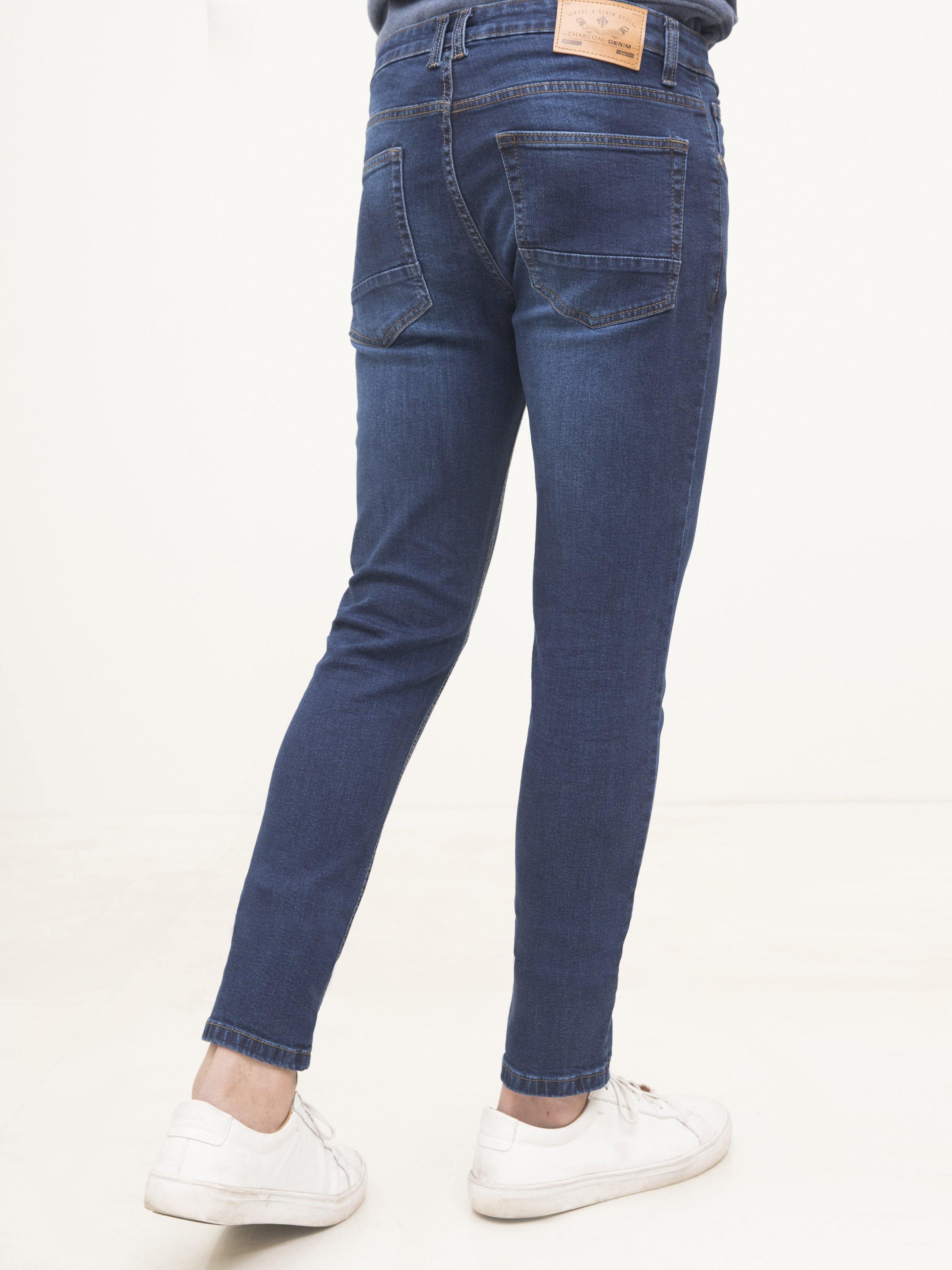 Dark blue slim-fit jeans, back view, stitched rear pockets, tapered ankle