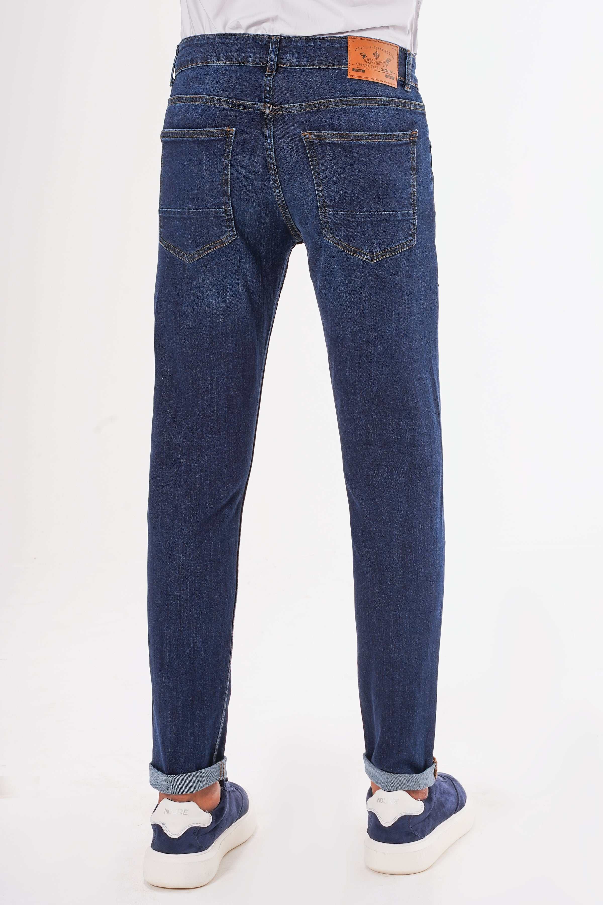 Dark blue slim-leg jeans with back patch pockets and orange logo label at waistband