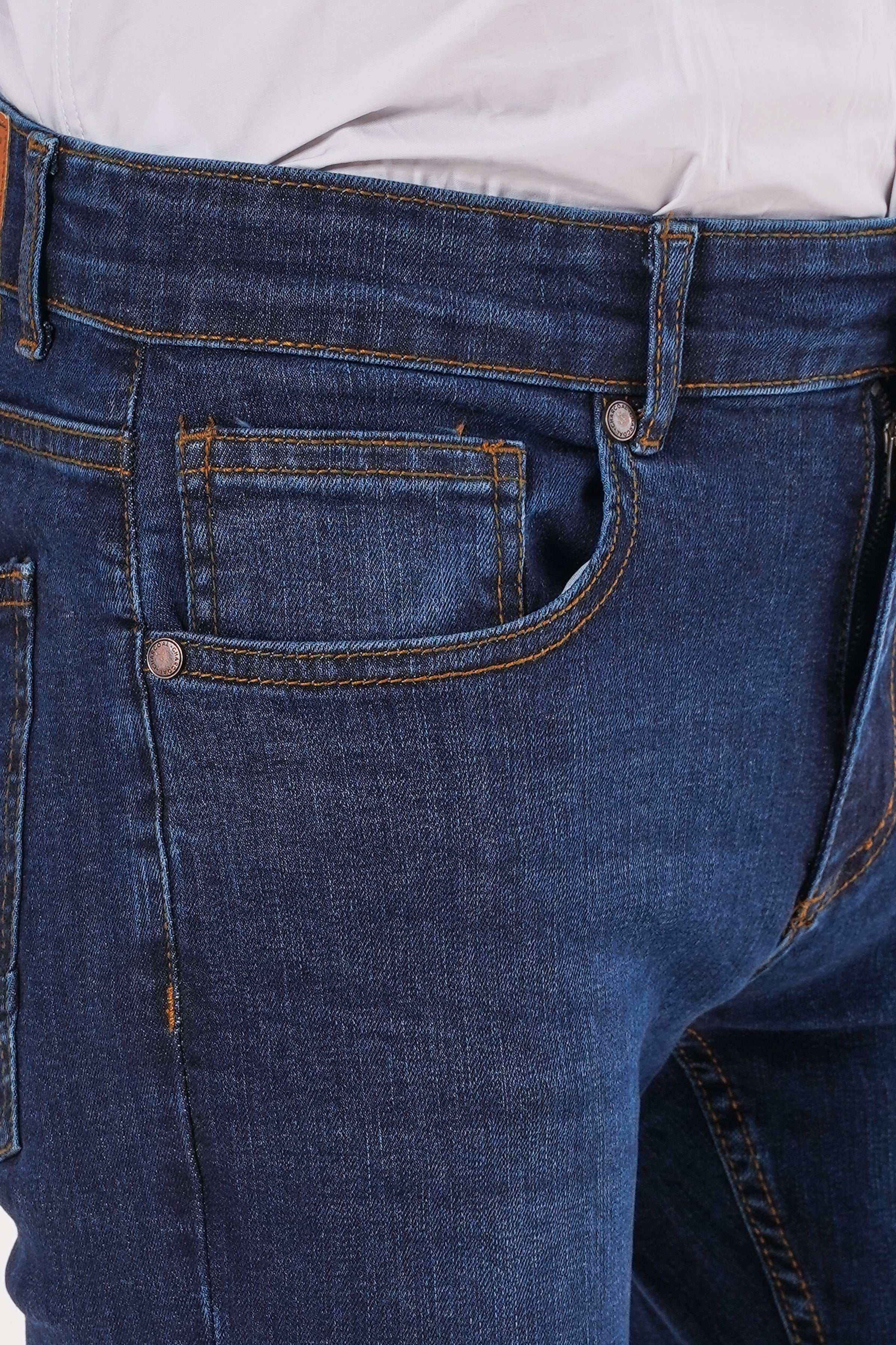 Dark blue denim jeans detail: front pocket, contrast stitching, and buttoned fly