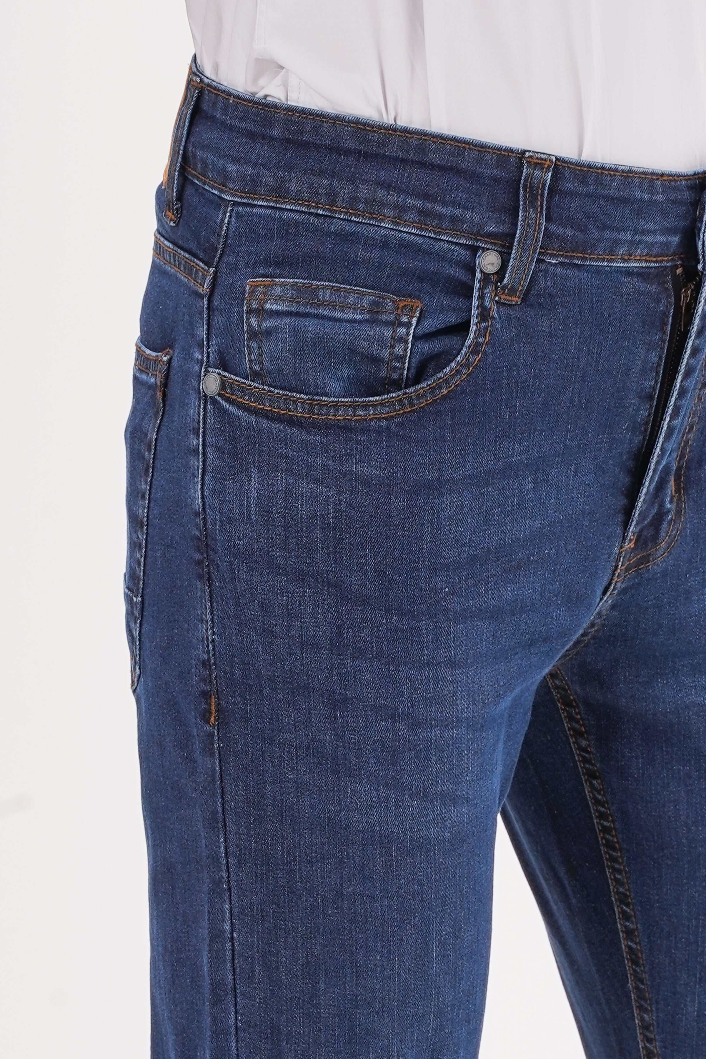 Mid-blue slim jeans close-up of front pocket, rivets, and curved coin pocket.