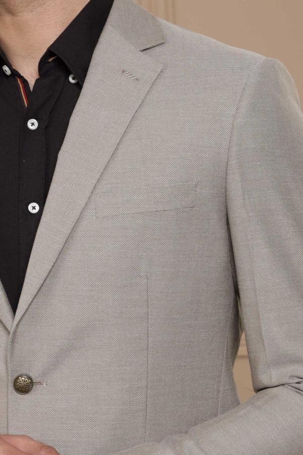 Close-up of light brown blazer lapel, chest pocket, and buttoned front