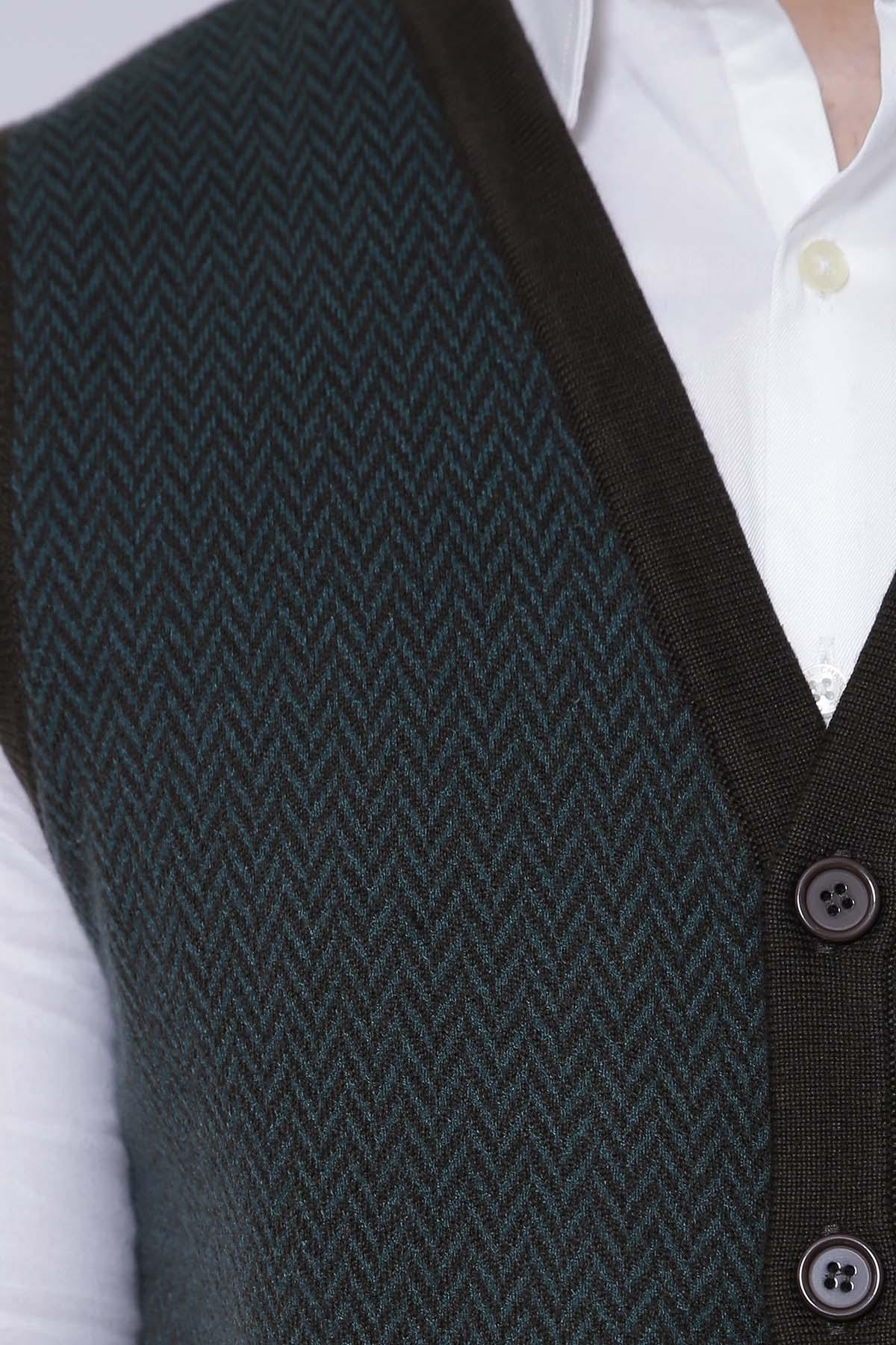 Close-up of dark green knit sleeveless cardigan with textured pattern and button