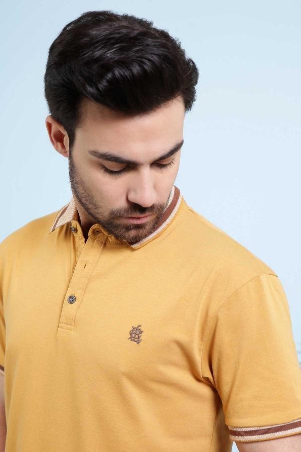Mustard polo shirt close-up with chest logo, button placket, and striped collar edge