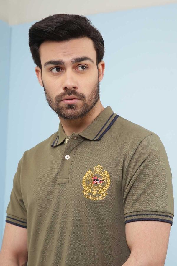 Olive green polo T-shirt front with crest emblem and dark striped tipping at cuffs.