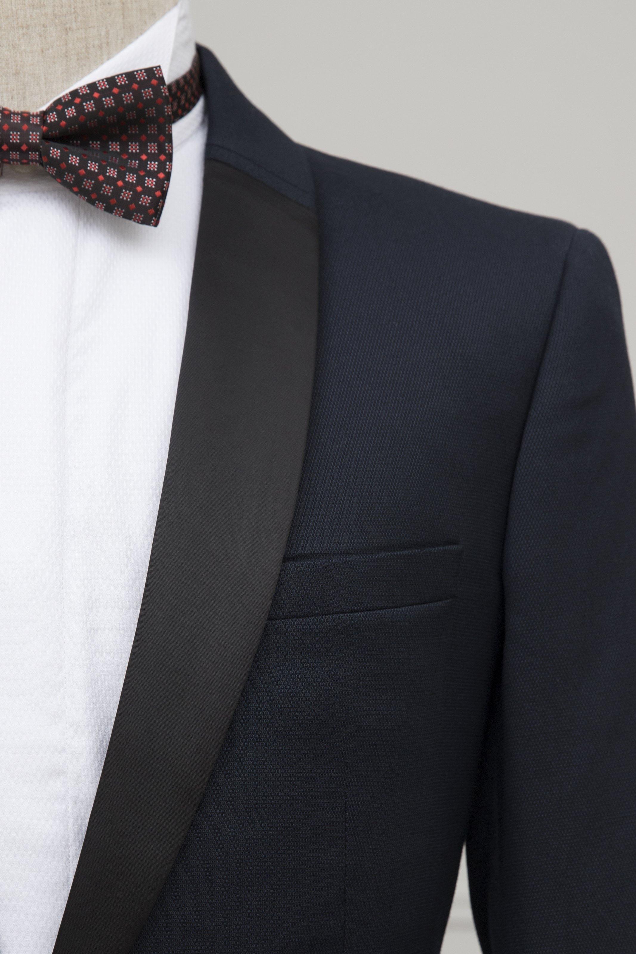 Navy tuxedo jacket lapel with bow tie and matching trousers on mannequin