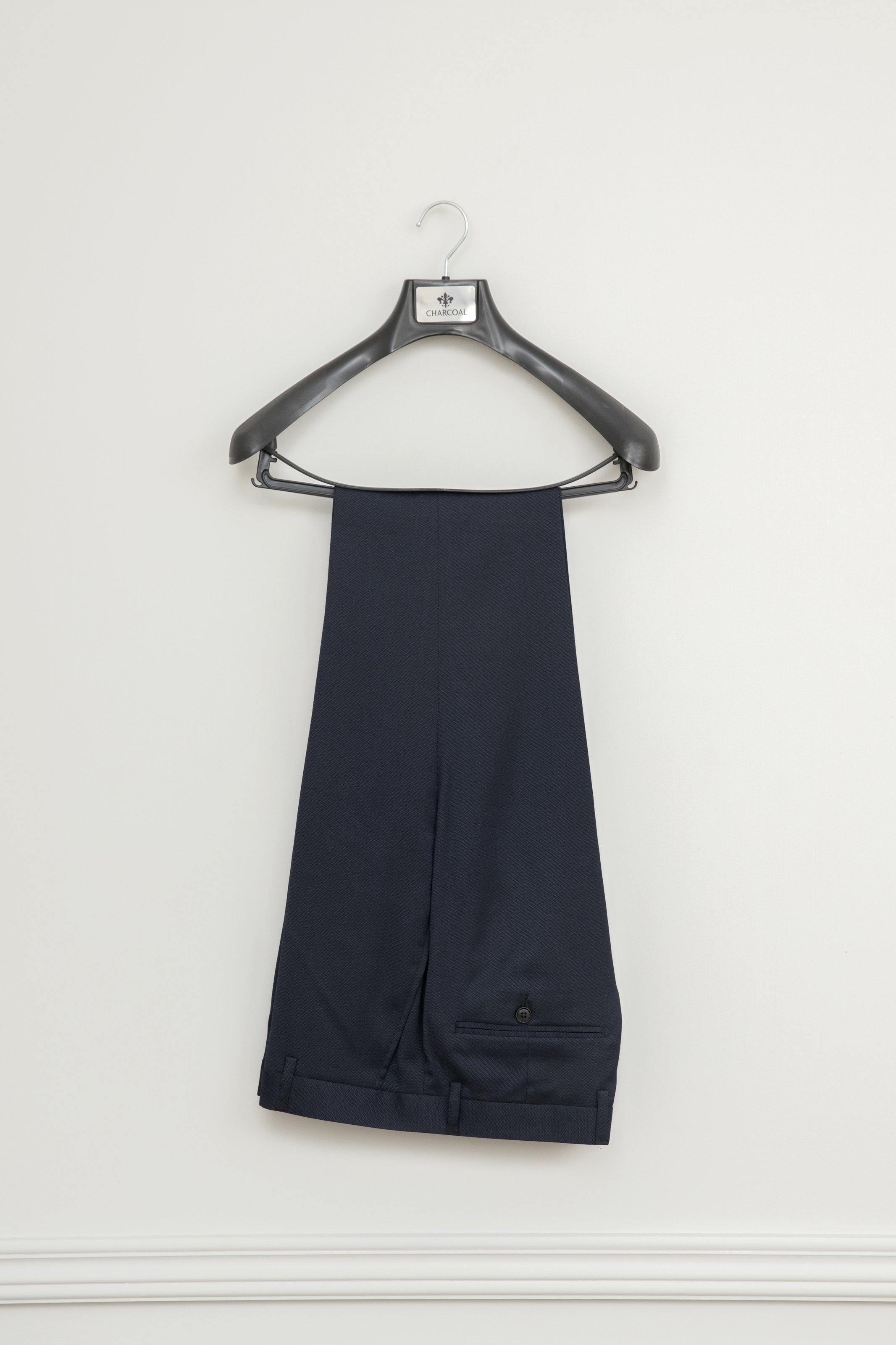 Navy tuxedo pants with front crease and cuffs, hanging on a hanger