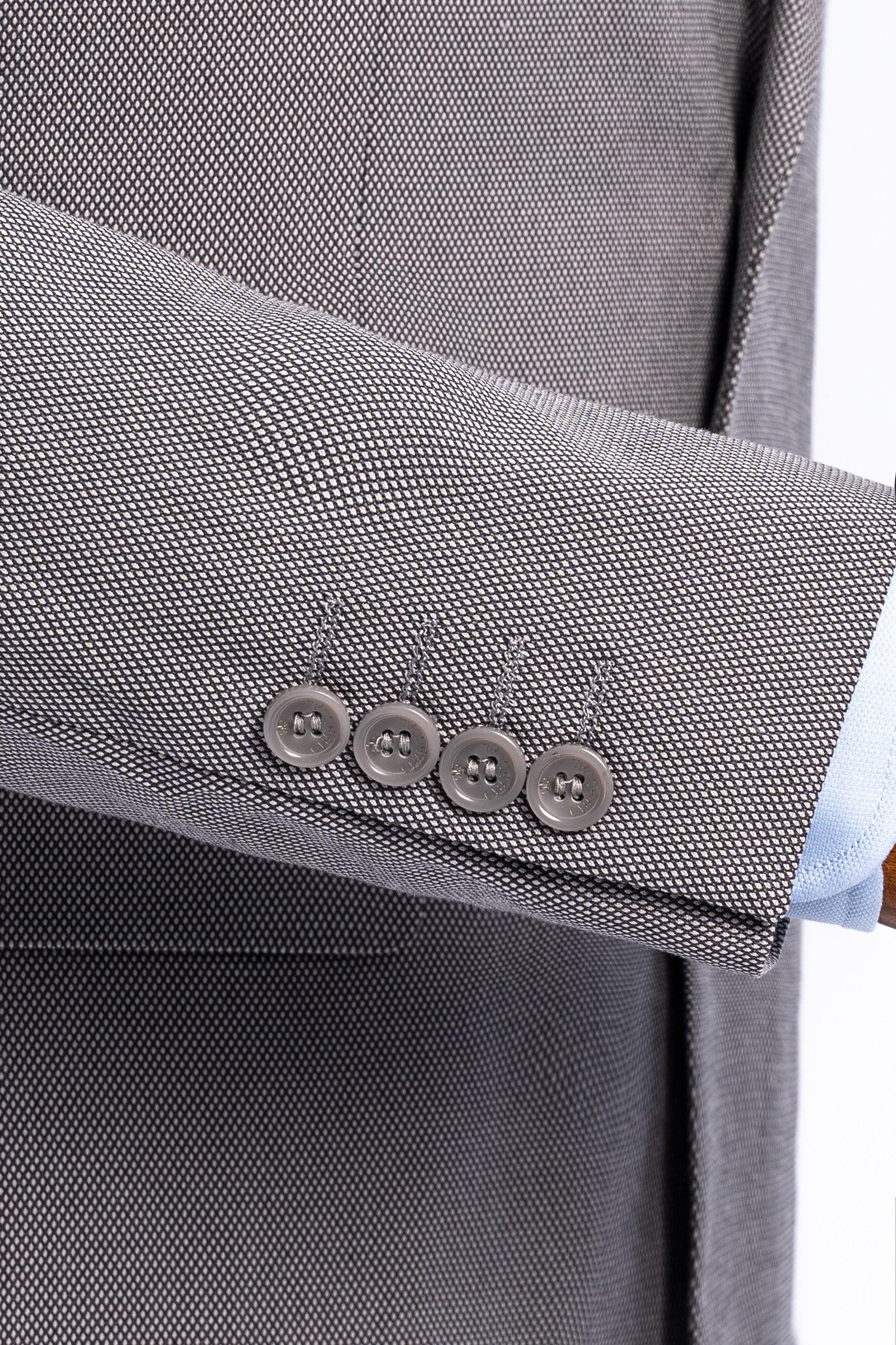 Suit jacket sleeve cuff in medium gray with four buttons over a light dress shirt