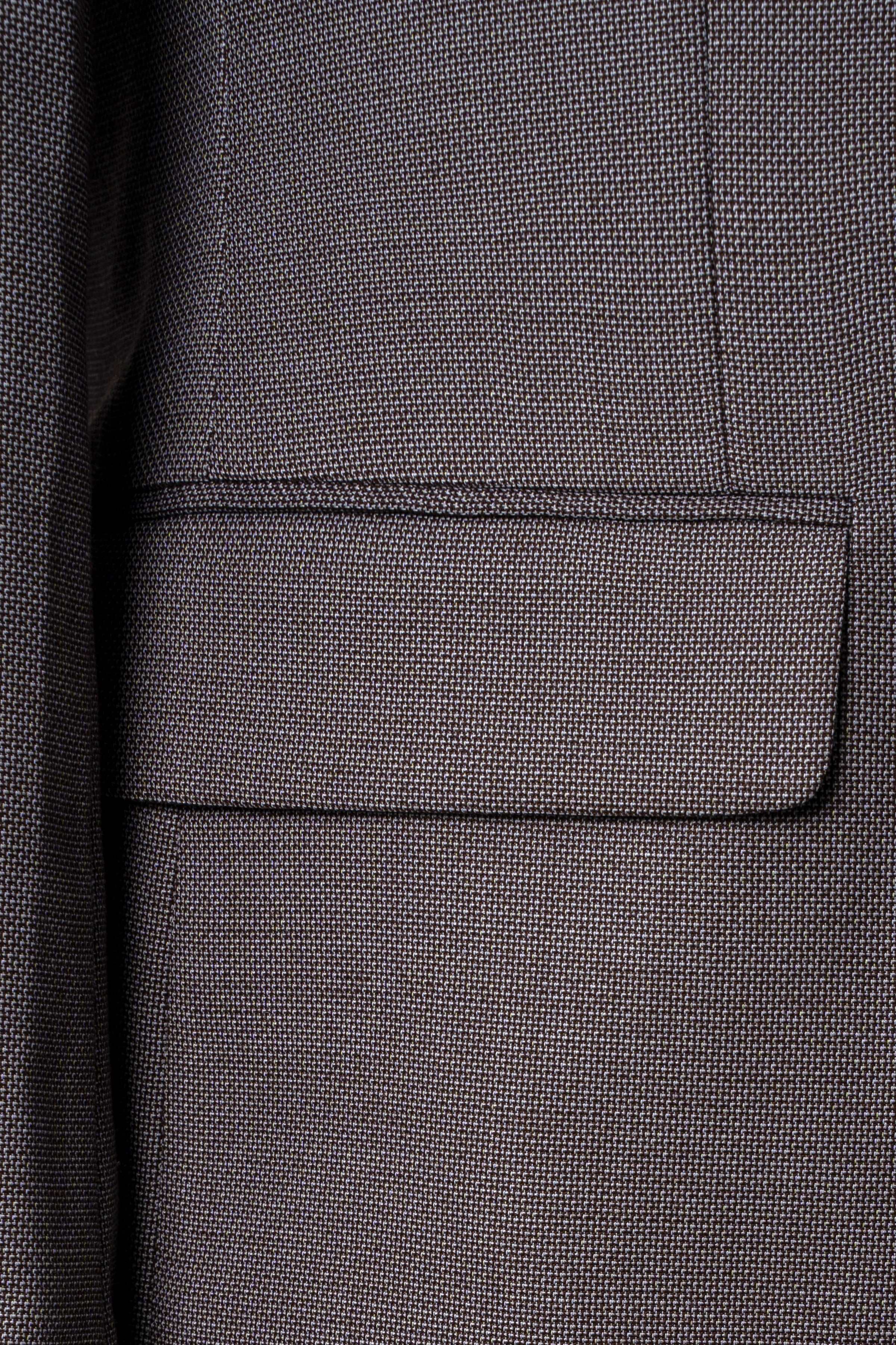 Grey suit jacket pocket with flap and fine textured fabric weave detail