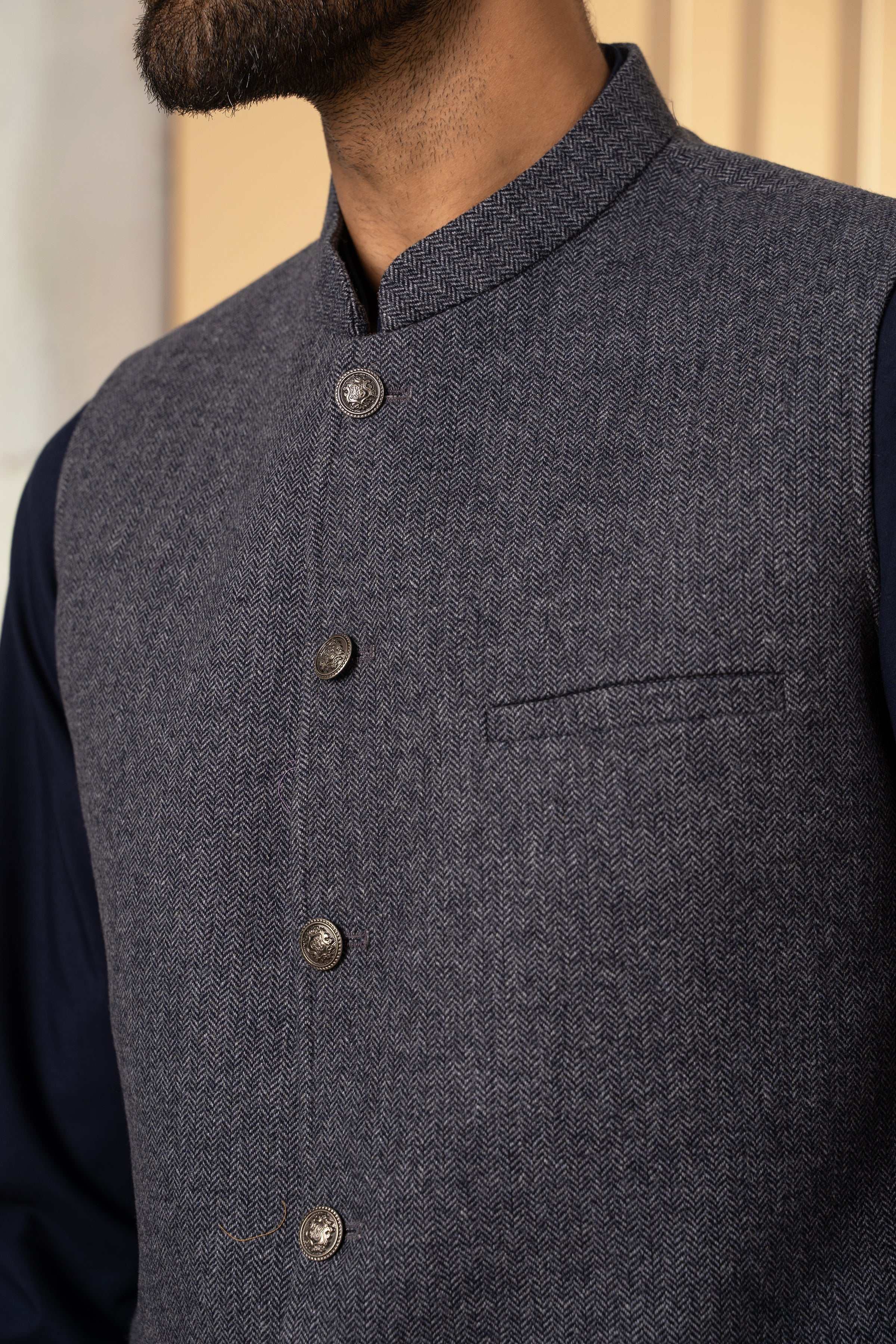 Grey herringbone waistcoat close-up with brass buttons and chest welt pocket