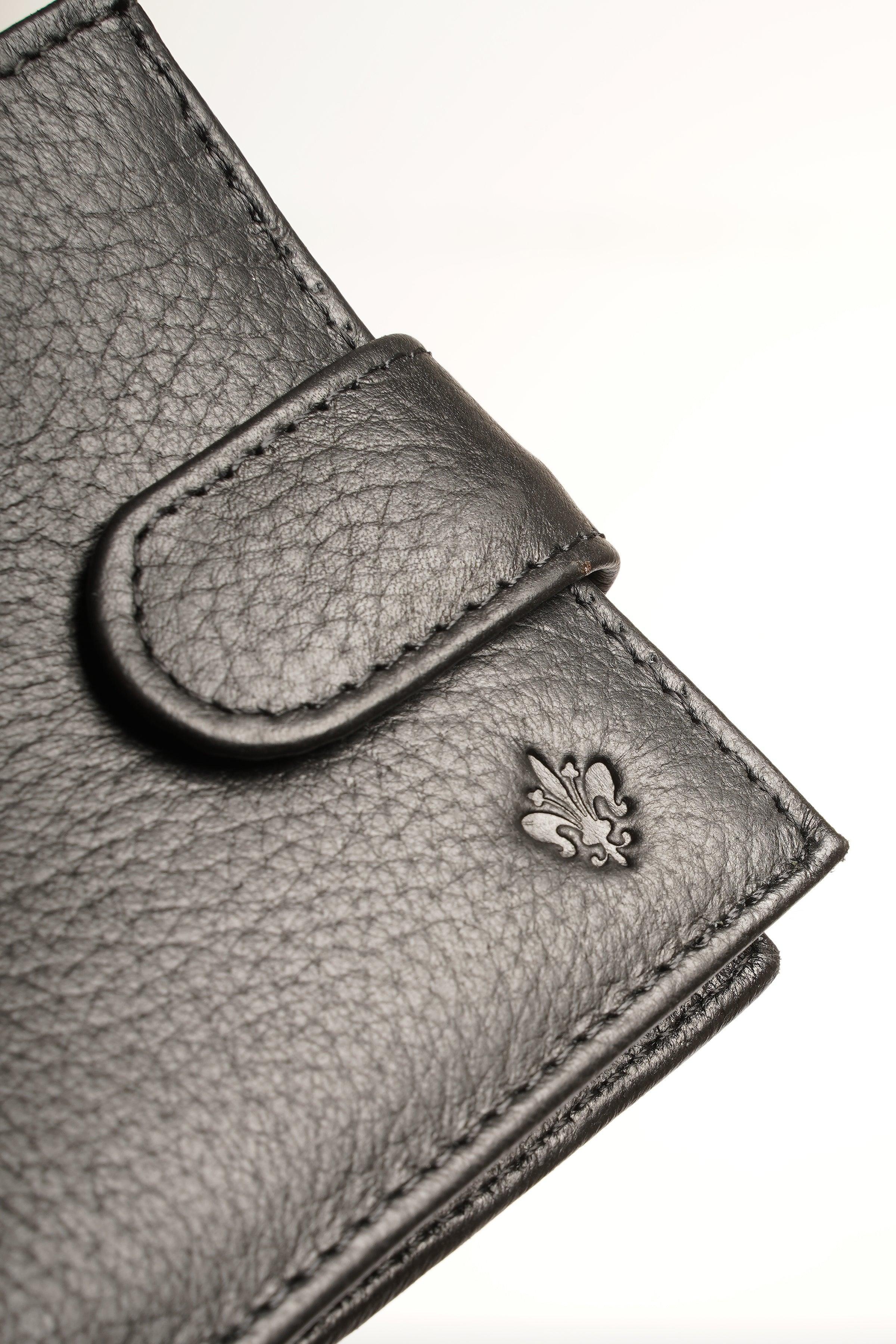 Black leather wallet corner detail with fleur-de-lis engraving and stitched edge