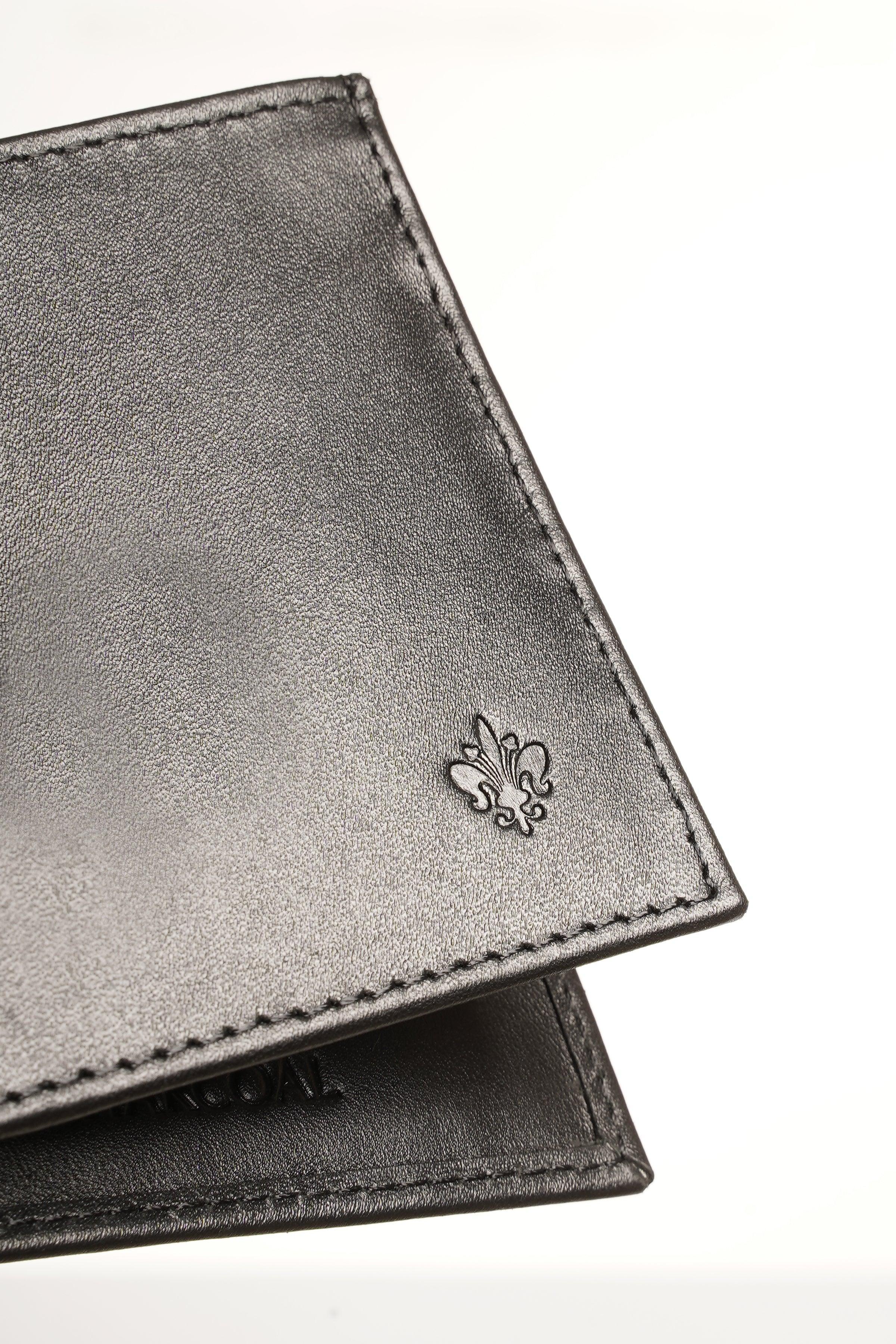 Black leather wallet corner close-up with embossed fleur-de-lis emblem