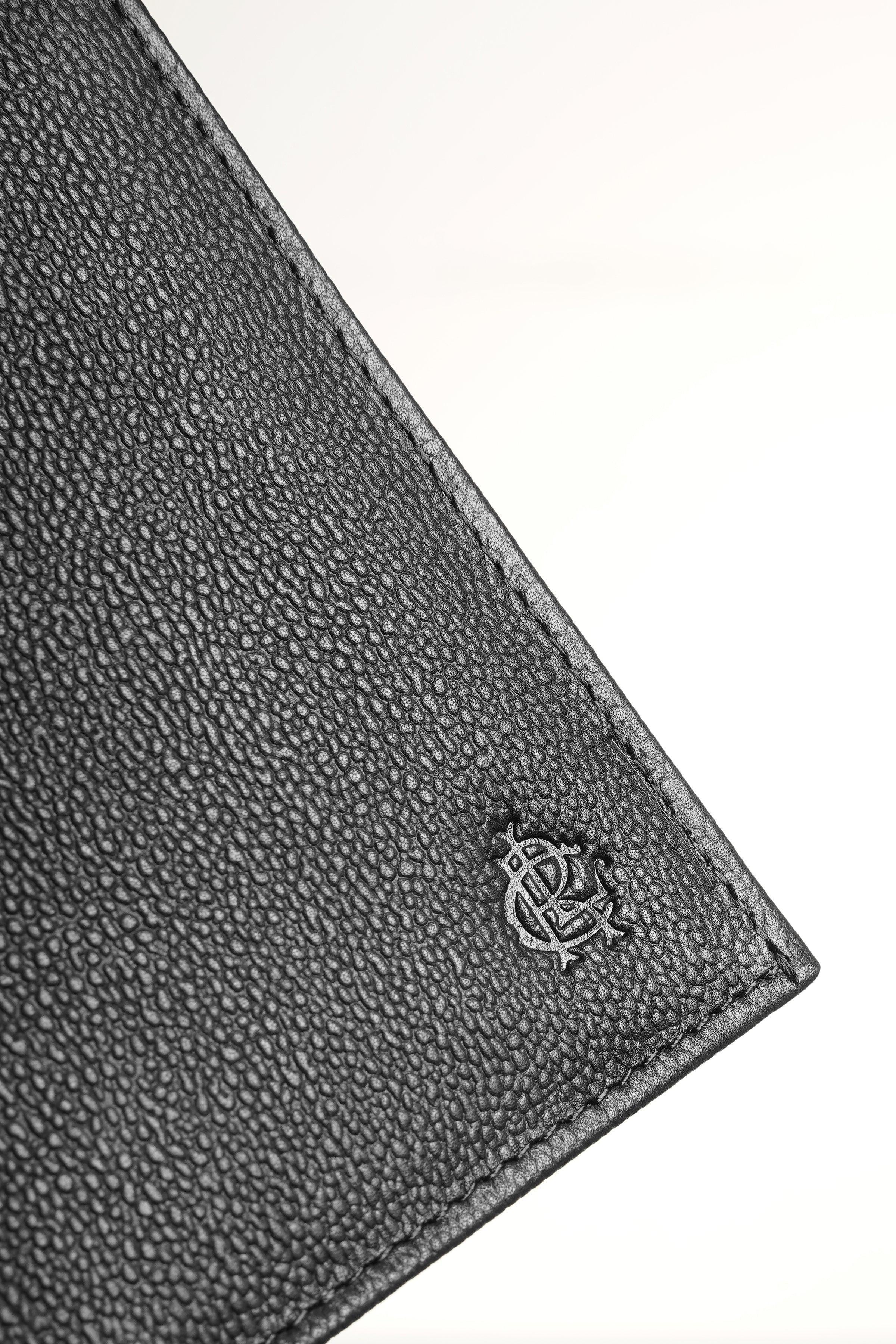 Black leather wallet corner close-up with embossed logo