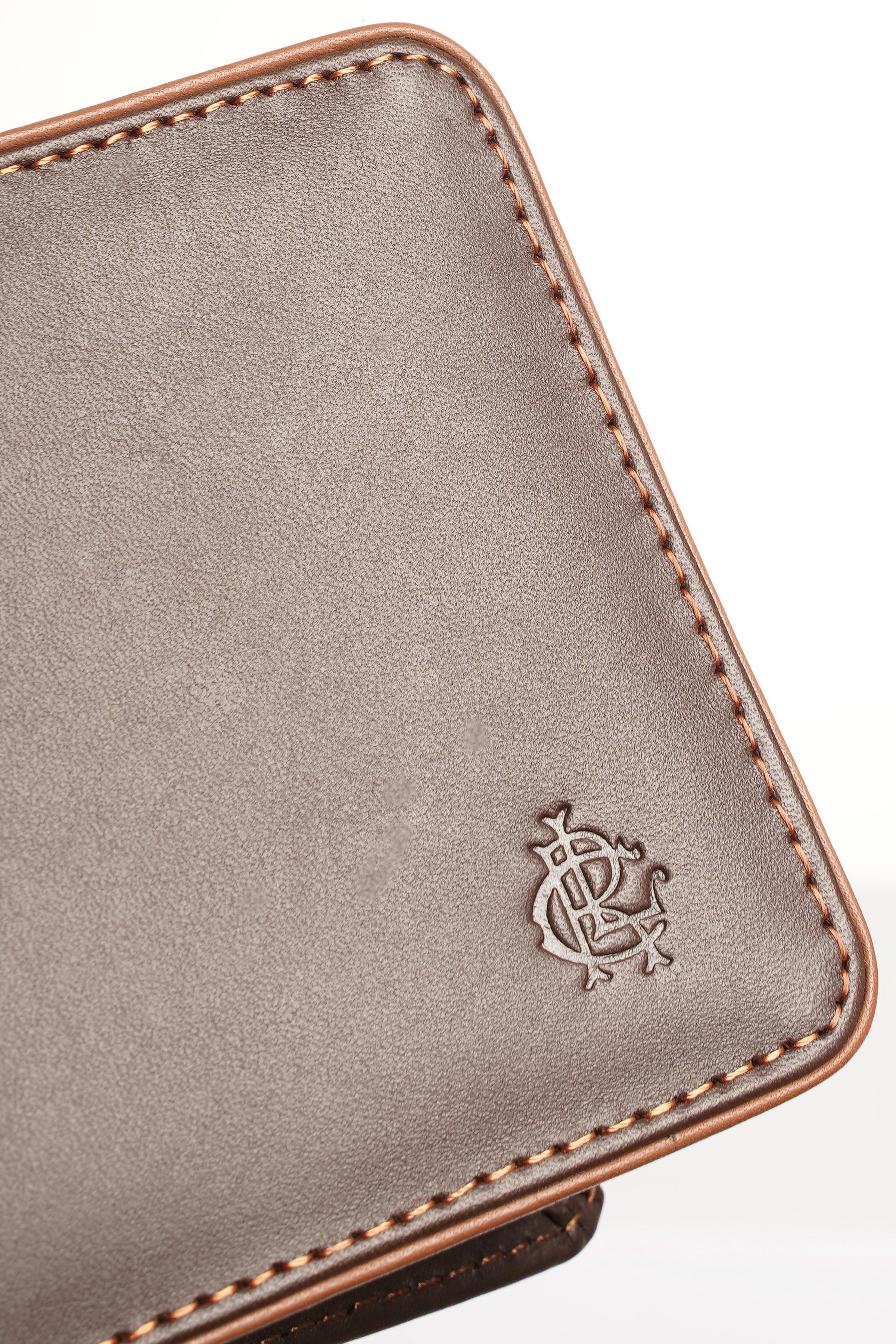 Brown leather wallet close-up with embossed emblem and contrast stitching