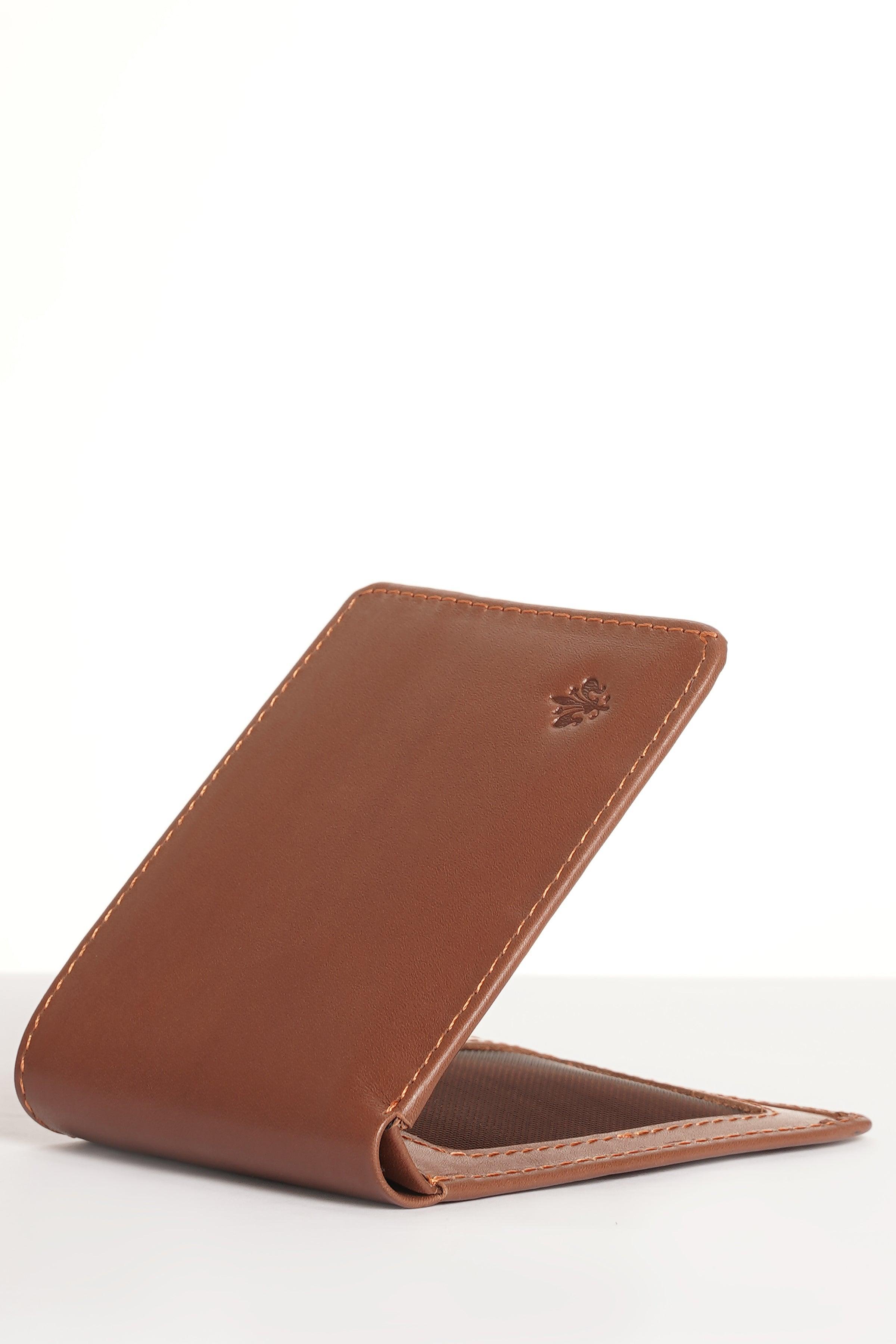 Tan bifold wallet standing, with leaf emblem and stitched strap