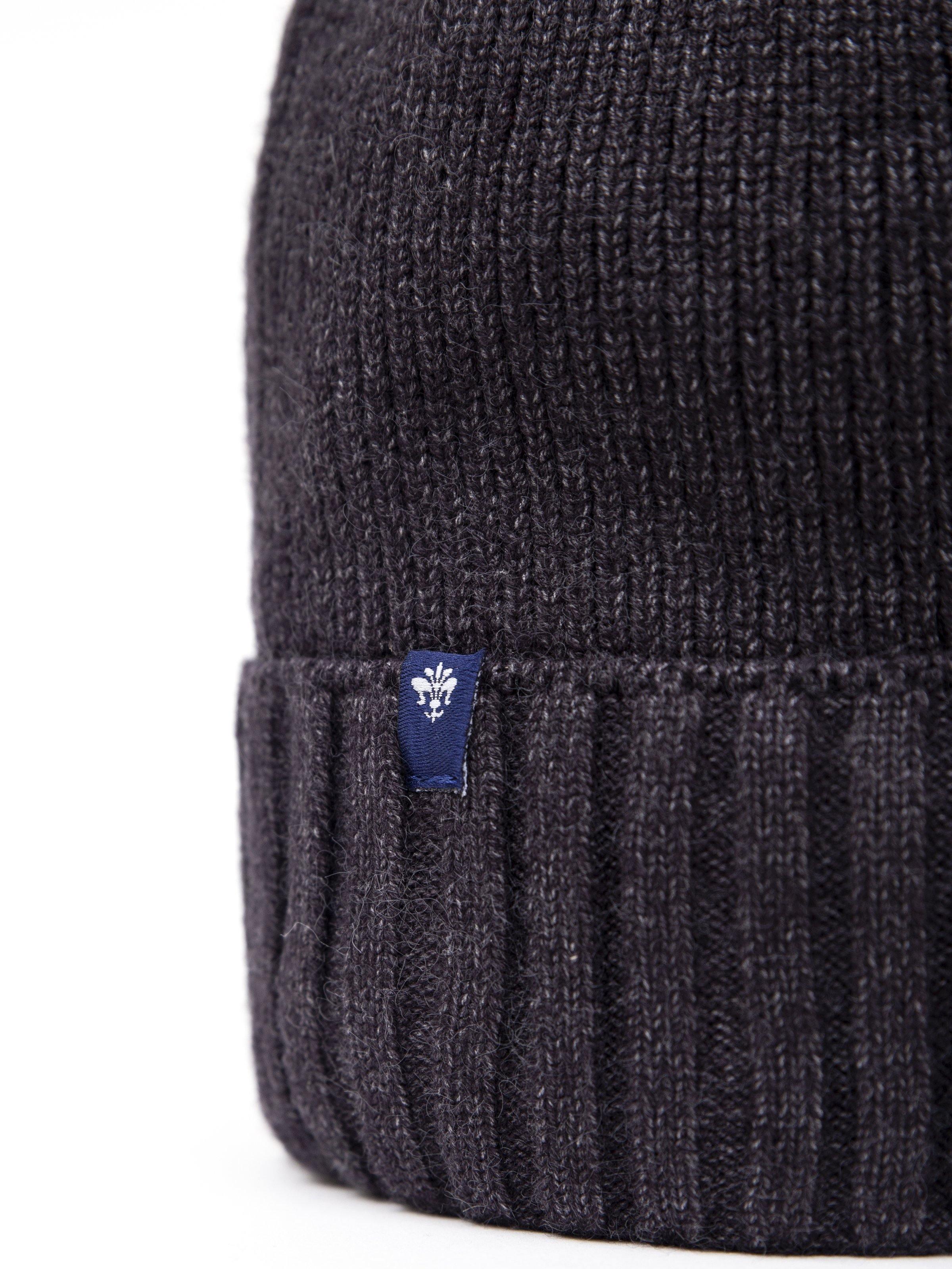Dark wool cap close-up: ribbed knit cuff with blue logo patch
