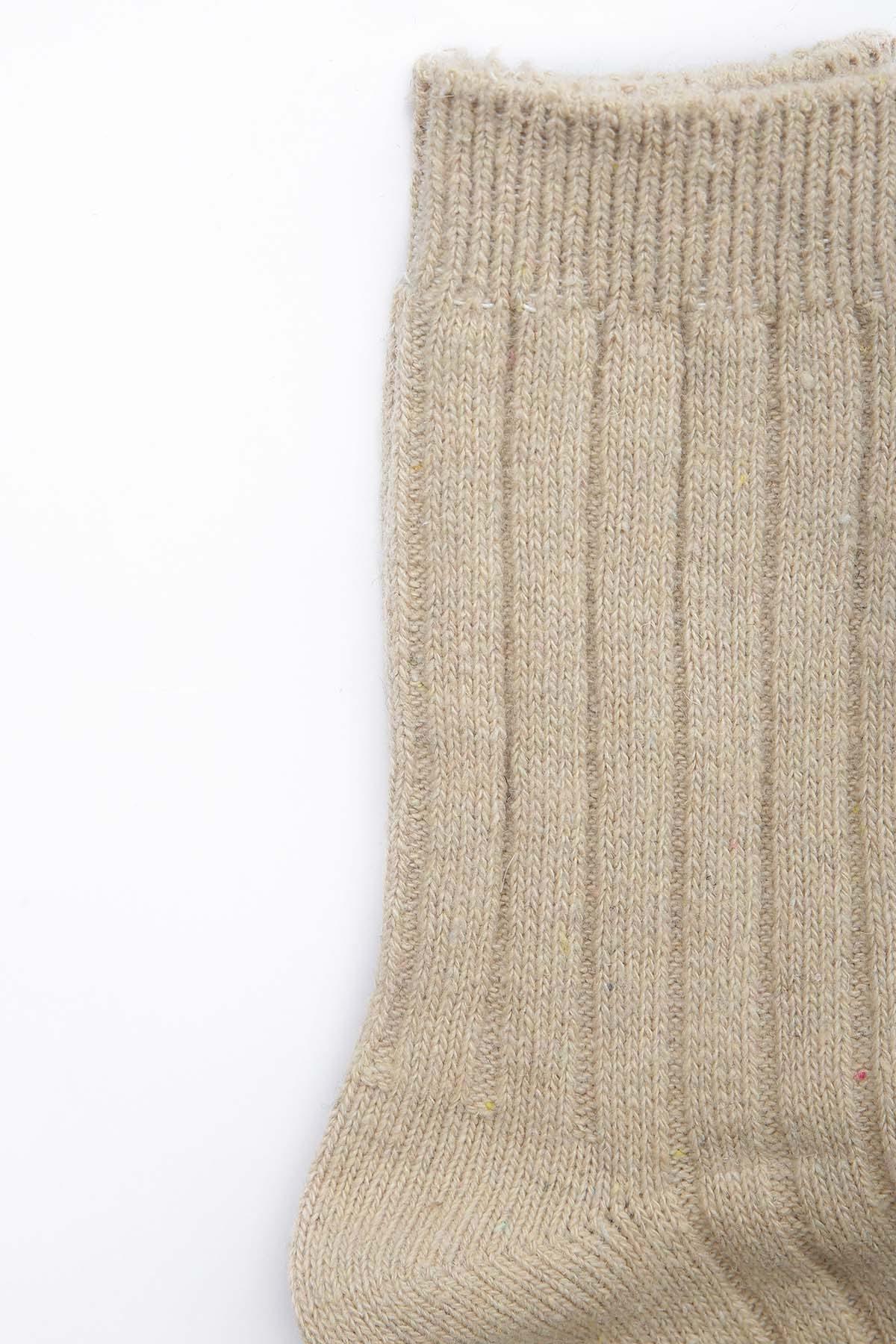 Beige wool sock with ribbed cuff and vertical knit texture, crew length