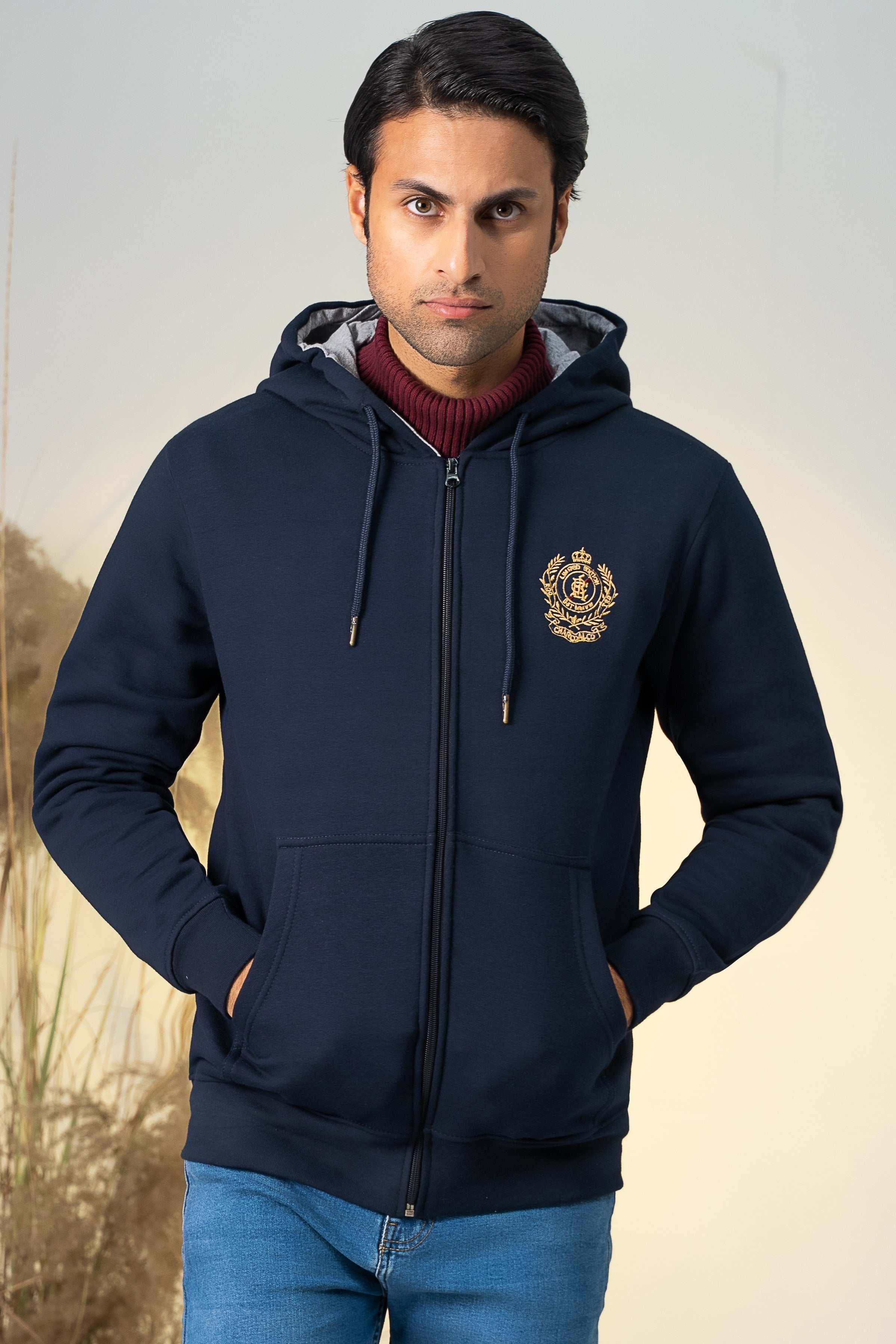 Navy zip-up hoodie with hood, drawcords, and front crest