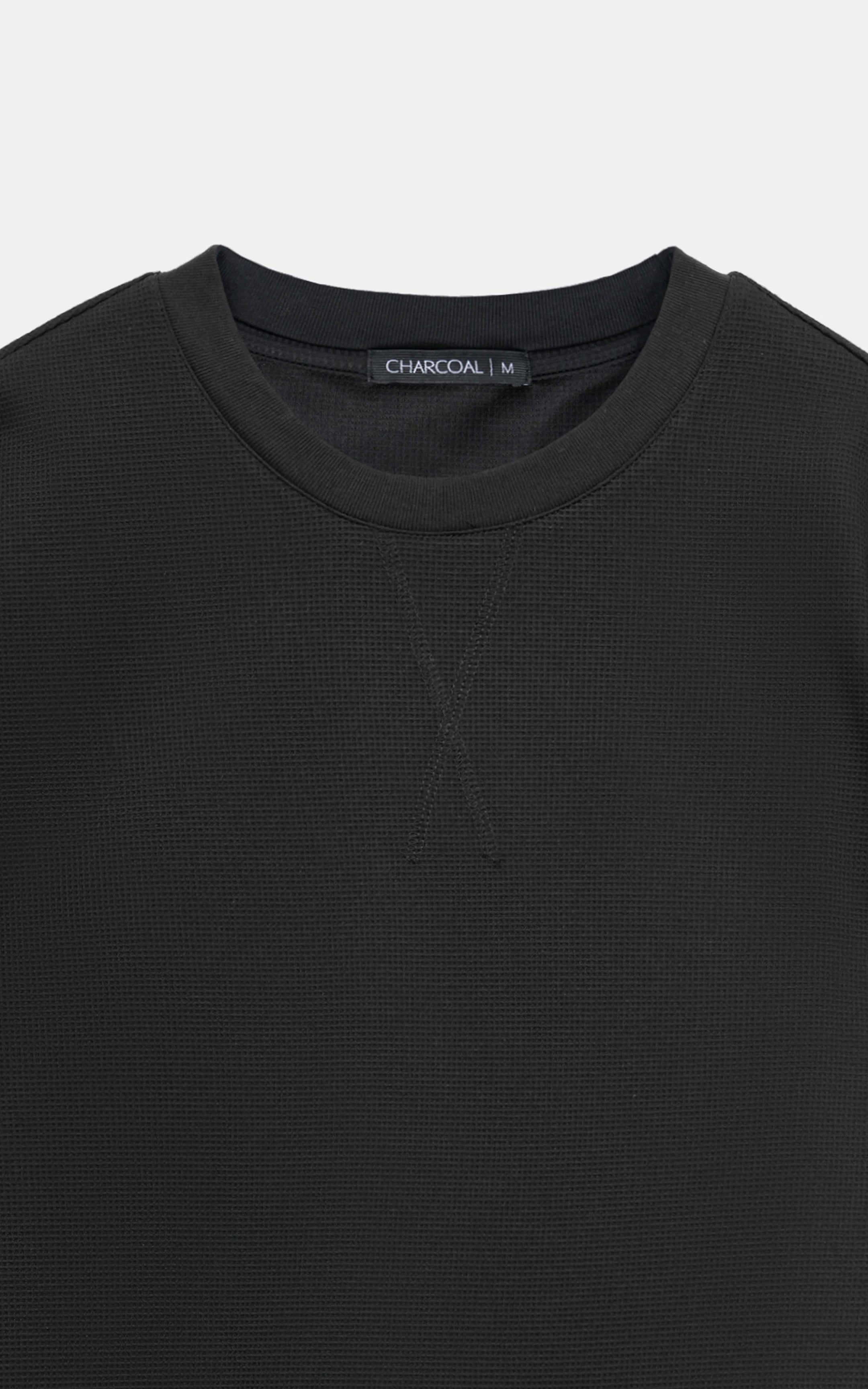 Black crew neck T-shirt close-up with subtle textured knit and ribbed neckline