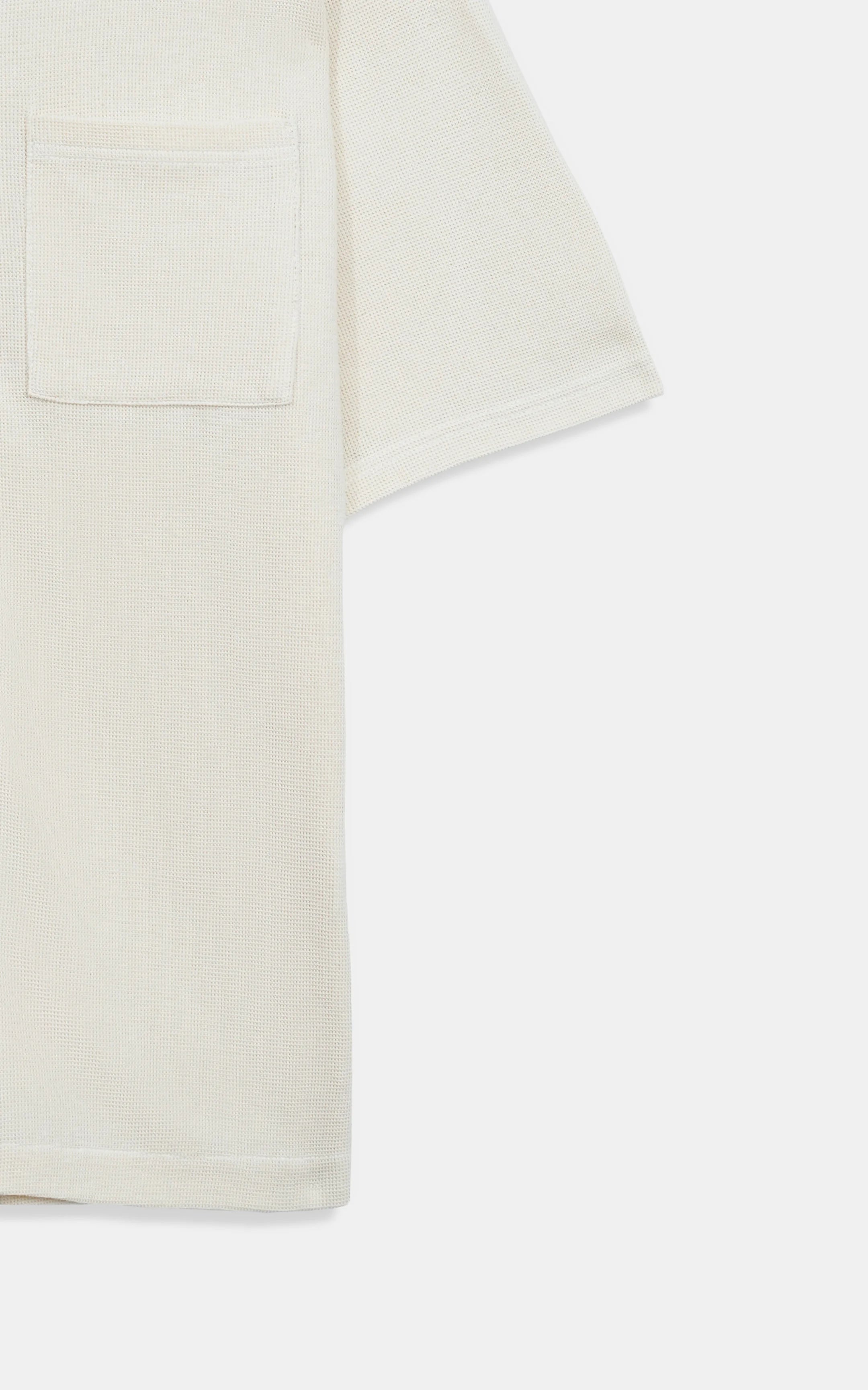 Off-white knit shirt fabric close-up with front pocket detail