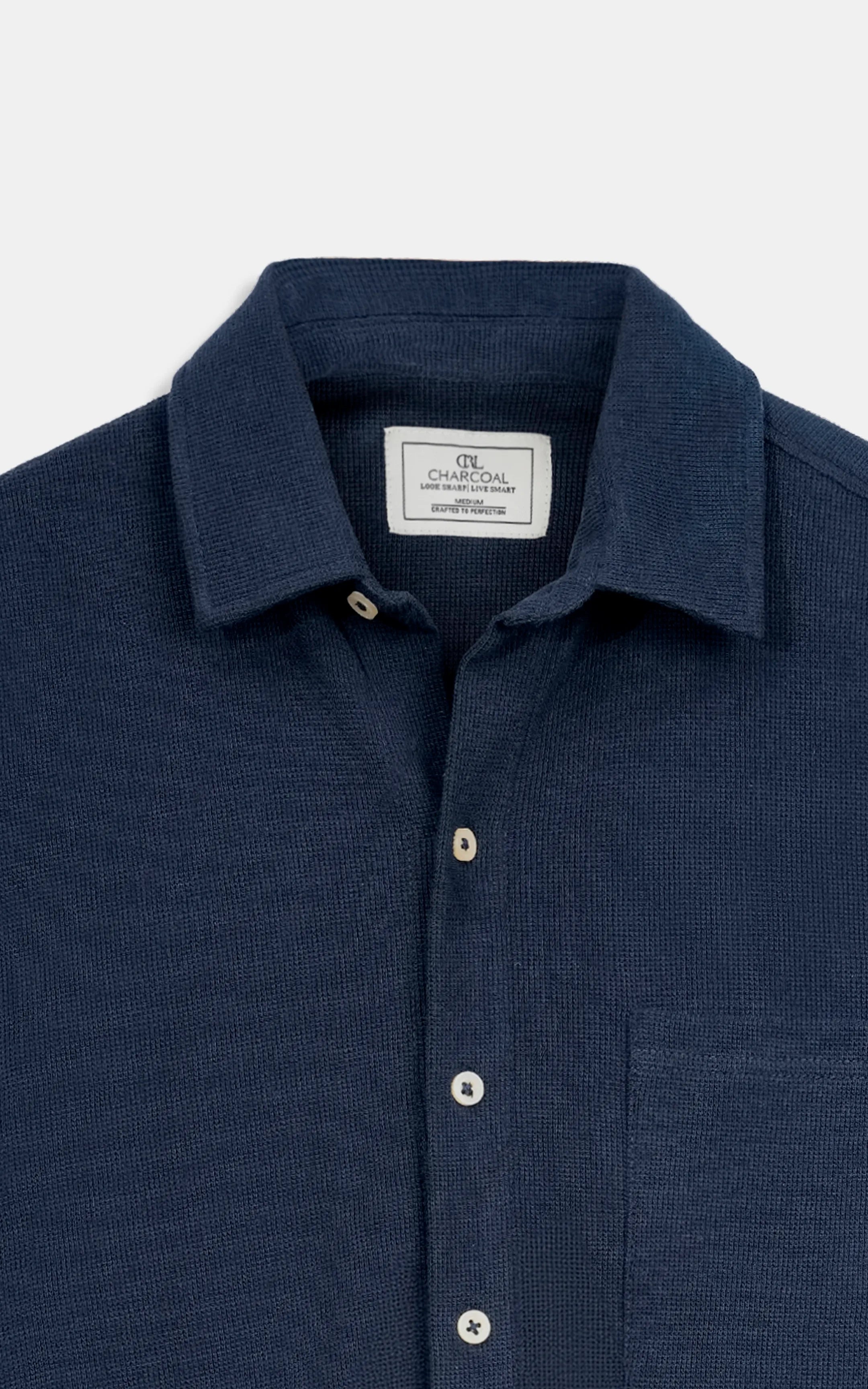 Navy knit button-up shirt close-up: pointed collar, logo tag, front buttons.
