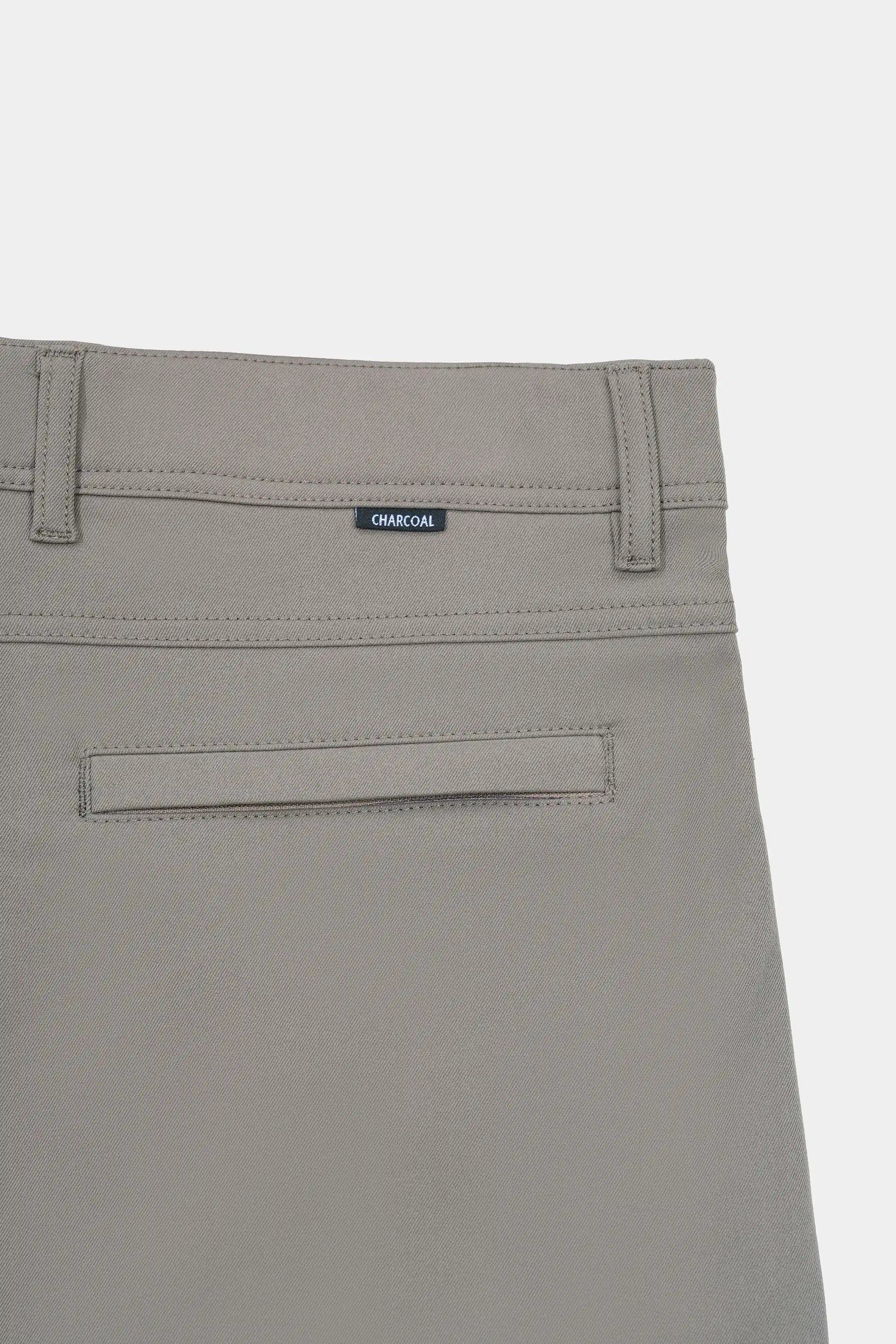 Straight-fit travel pants in light brown, close view of waistband label and front pocket seam.