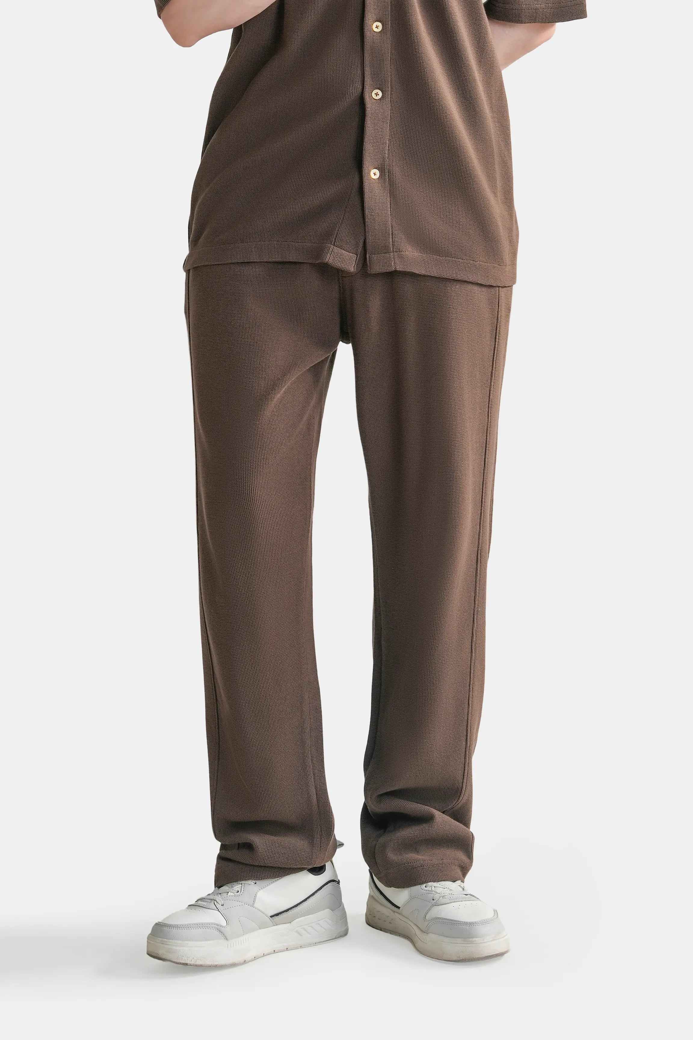 Brown knit trousers with relaxed fit, side pockets, and drawstring waist