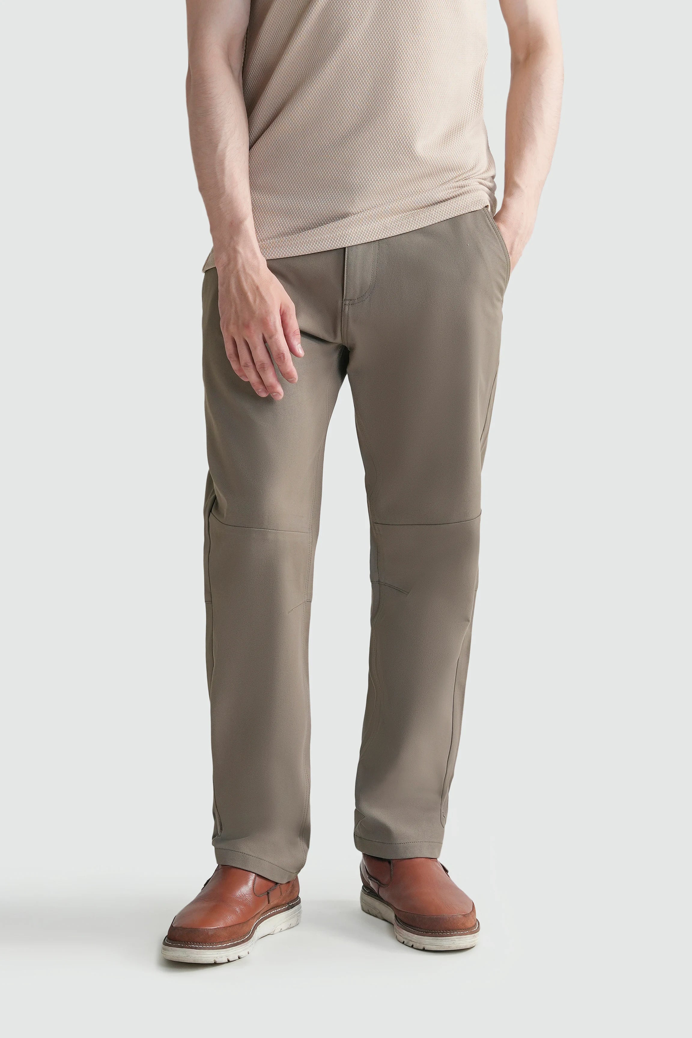 Straight-fit travel pants in light brown, worn with cuffed hem and side pockets.