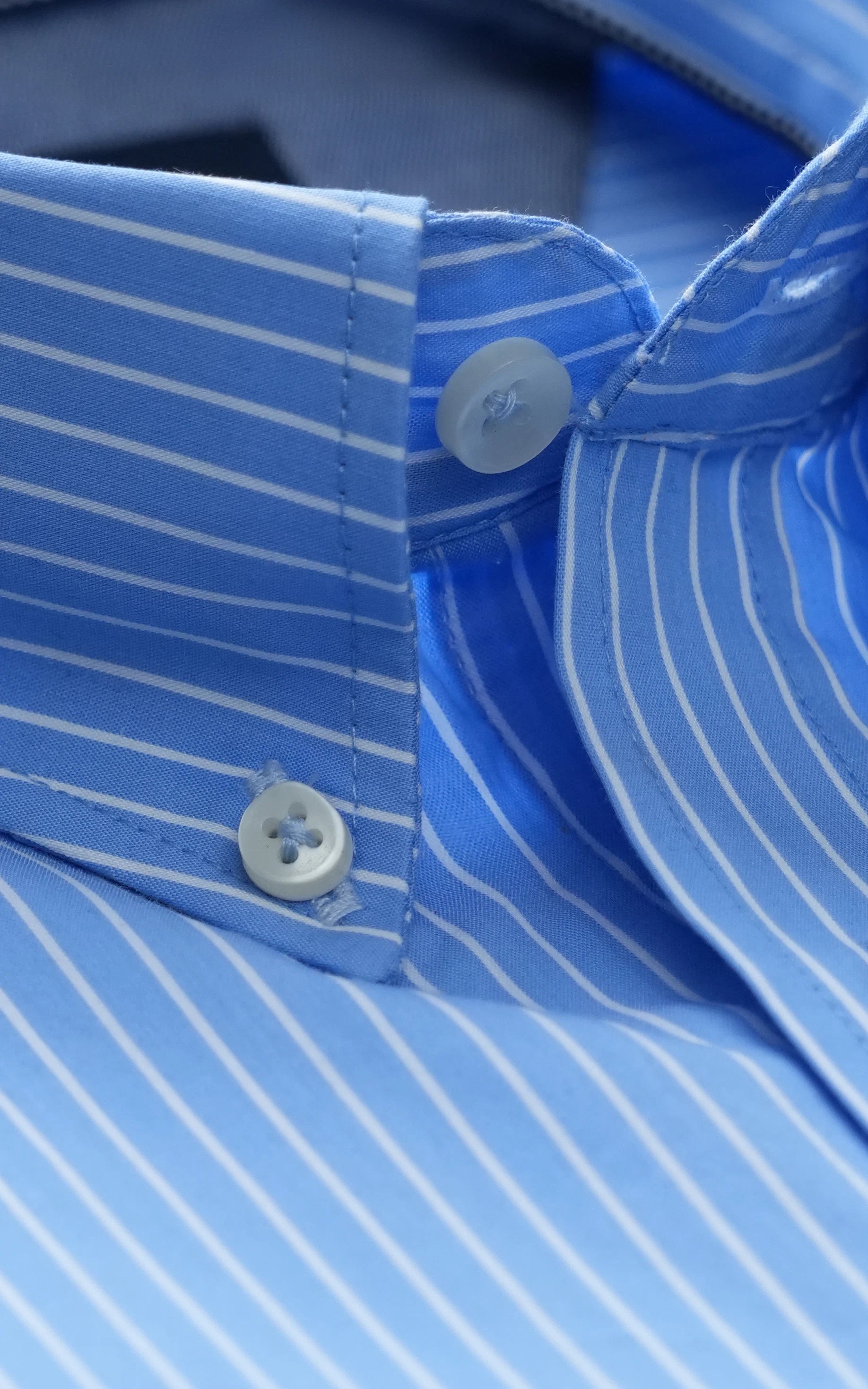 Light blue striped dress shirt close-up of placket and cuff with round buttons
