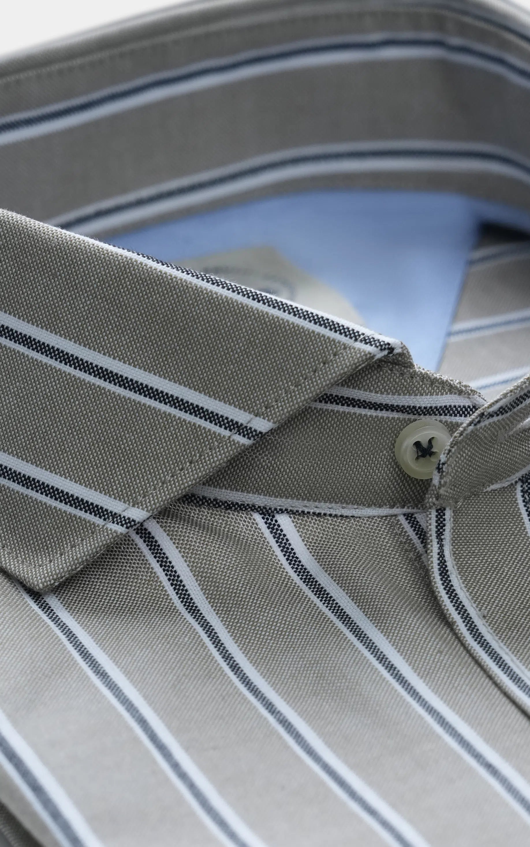 French-collar smart shirt detail: blue-striped collar, front button, light green fabric