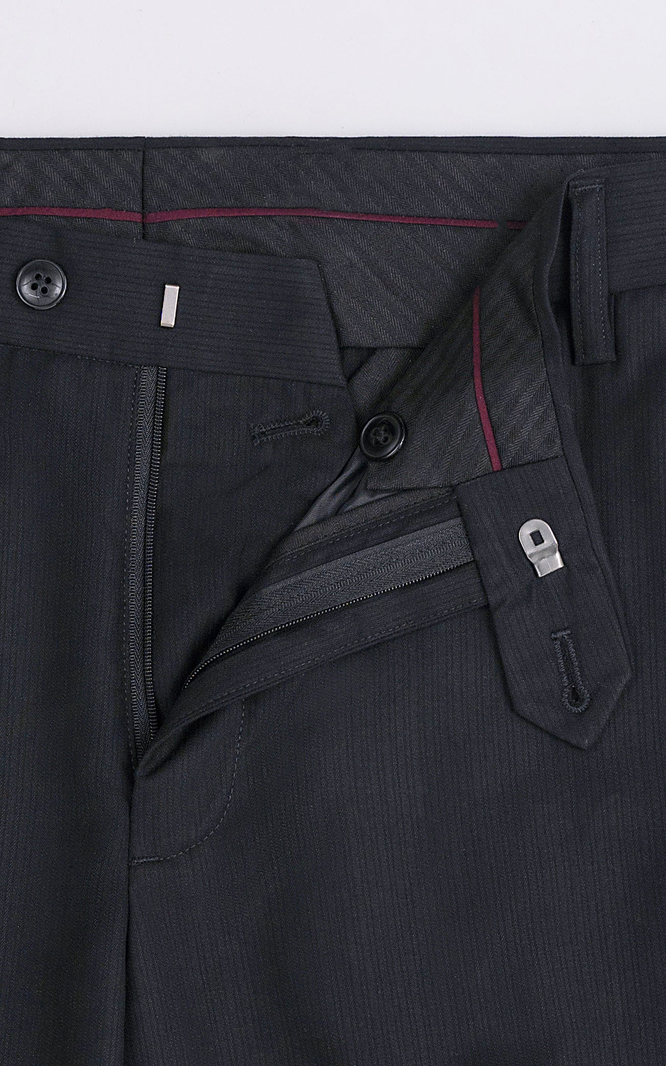Black dress pants detail: zipper fly, button, and slanted pocket