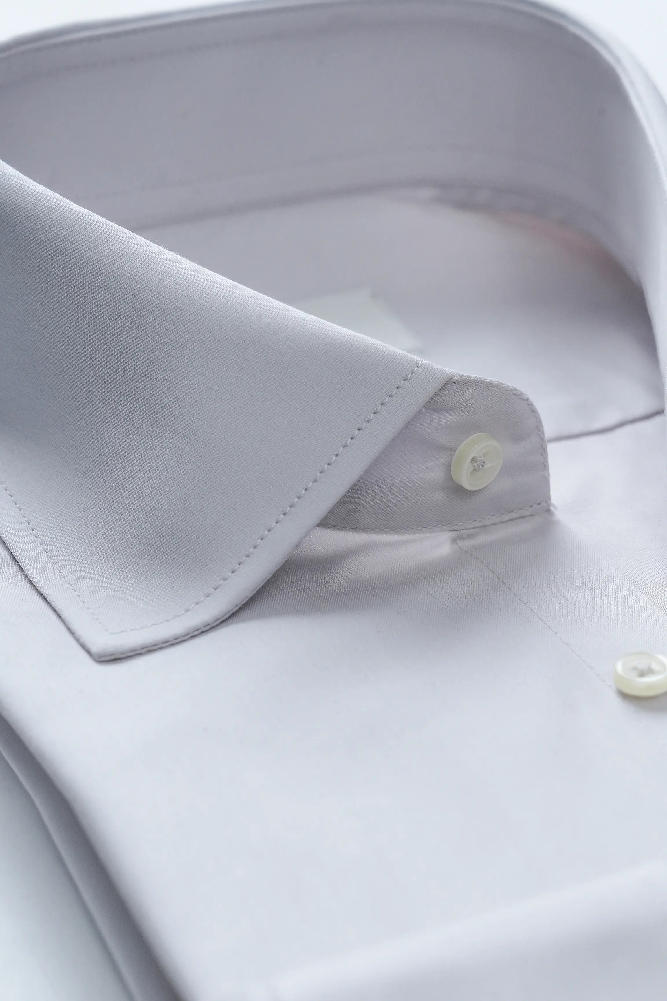 Light grey dress shirt collar detail with stitched seam and round button